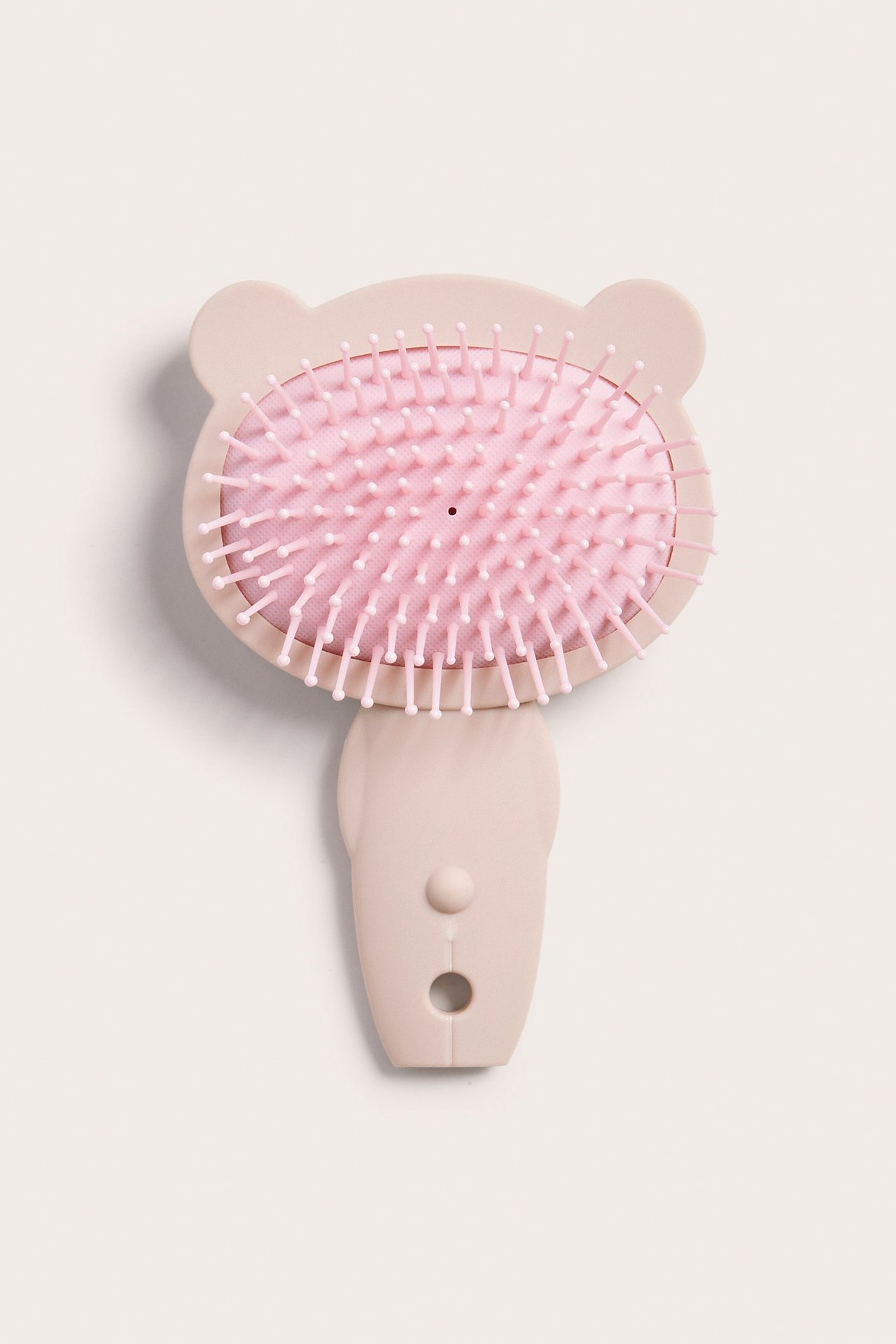 Widok z góry: jasnobeżowa plastikowa szczotka dla dzieci w kształcie głowy misia z różowym włosiem.