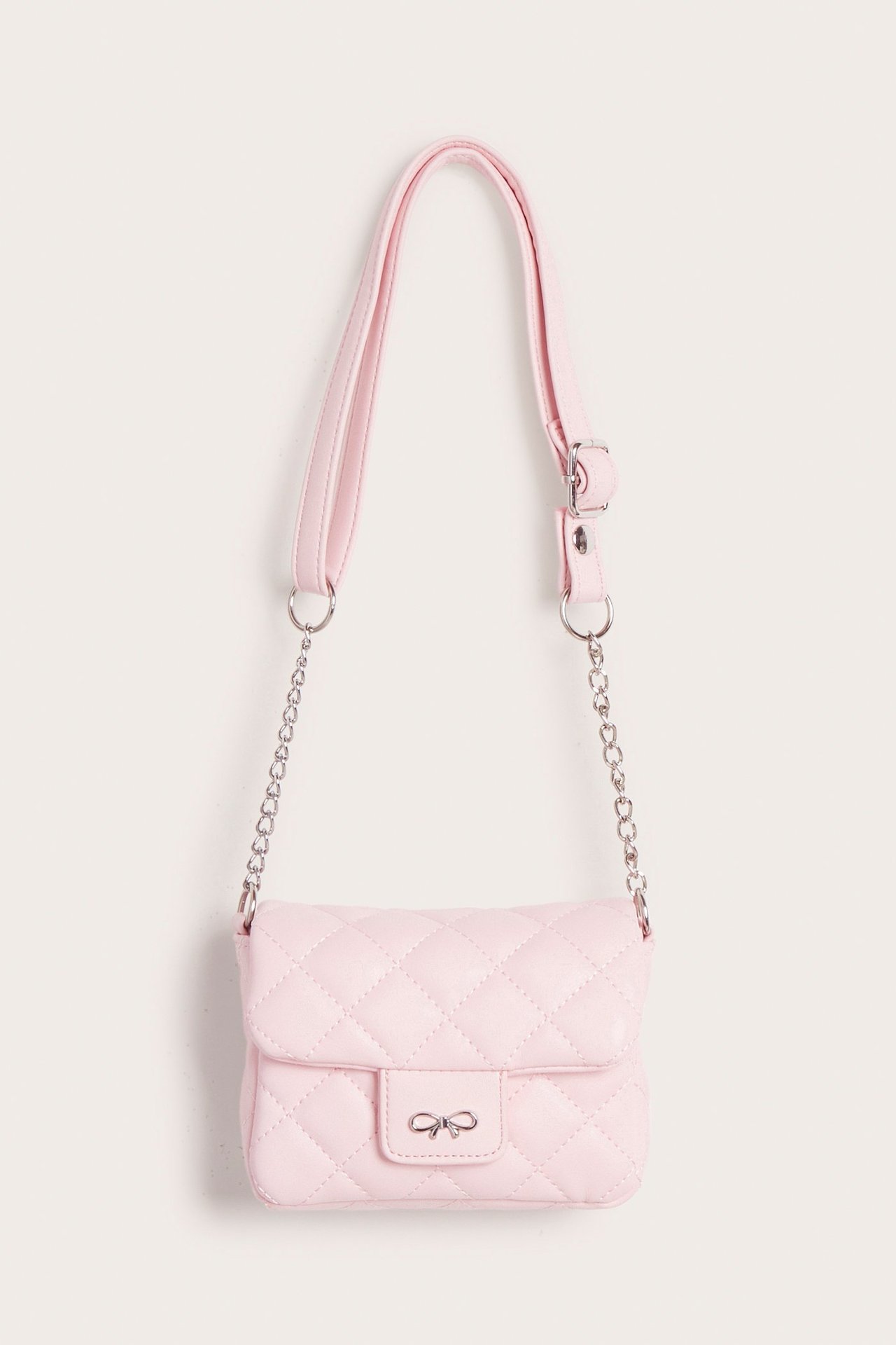 Edestä näkymä vaaleanpunaisesta tikatusta olkalaukusta, jossa hopeinen rusettilukko ja ketjuhihna.