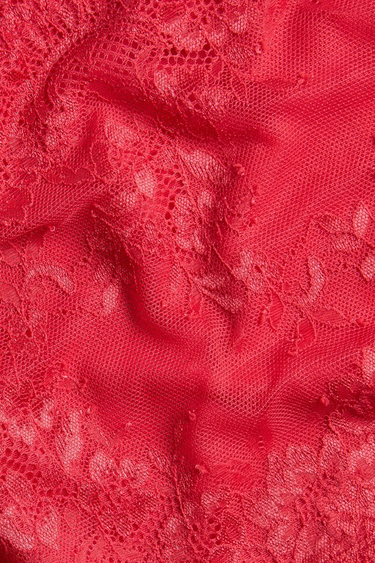 Zbliżenie na czerwoną koronkę z siateczkowymi detalami na stringi z wysokim stanem.