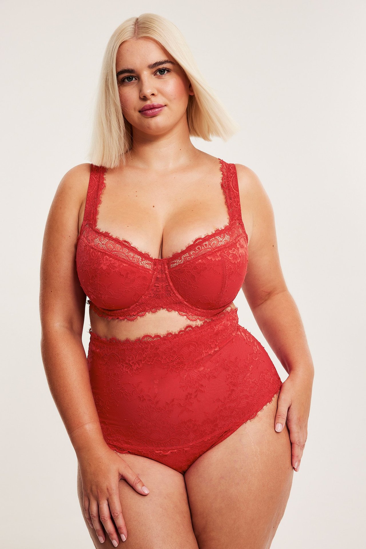 Widok z przodu: Kobieta w czerwonych koronkowych stringach z wysokim stanem i pasującym biustonoszu.