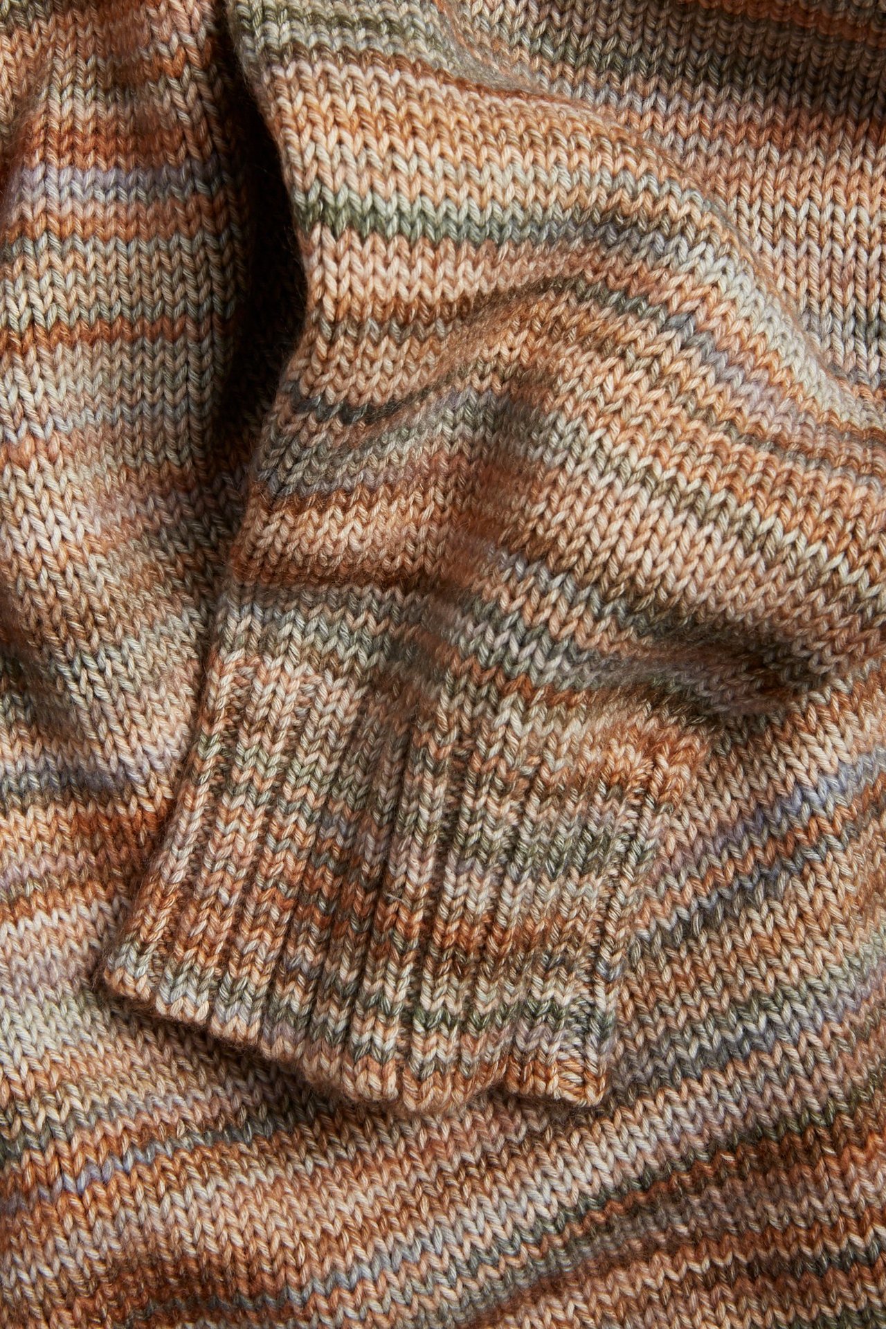 Zbliżenie na brązowy melanżowy sweter z dzianiny ze ściągaczem, wykonany z wielobarwnej przędzy.