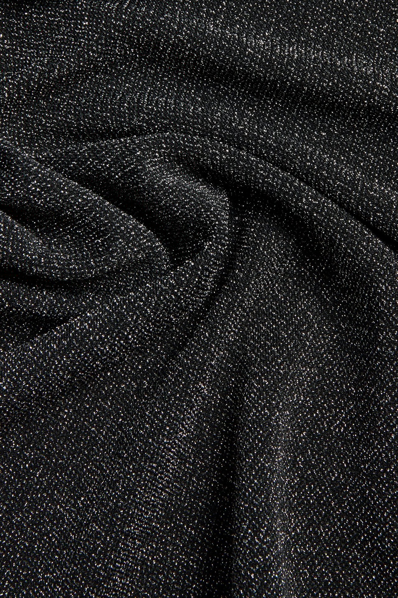 Zbliżenie czarnego, błyszczącego materiału krótkiej spódnicy, z metalicznymi nićmi i miękkimi fałdami.