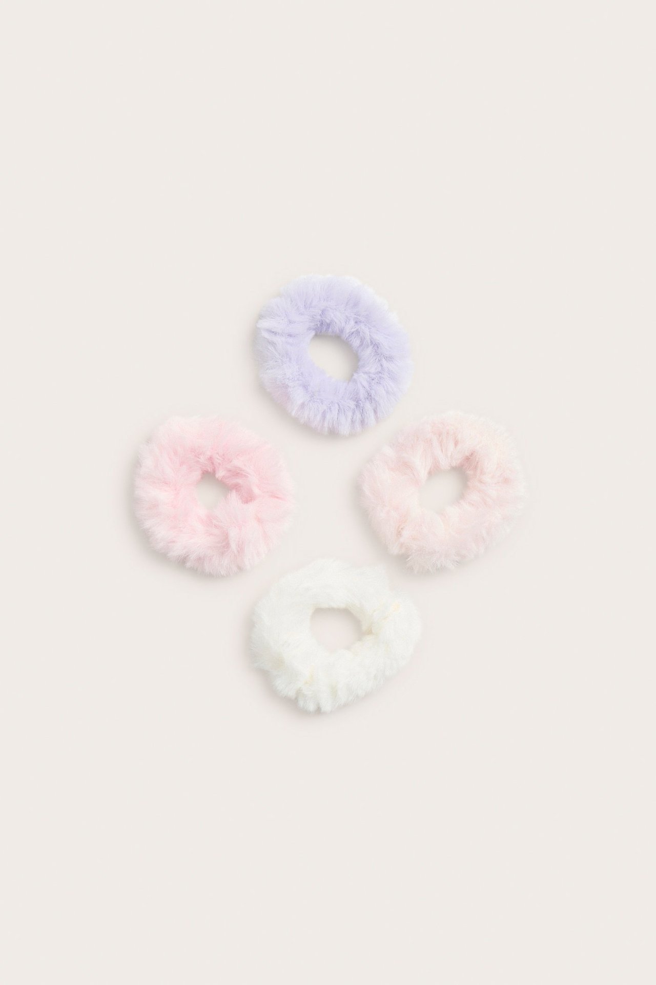 Lähikuva neljästä pörröisestä hiuslenkistä vaaleanviolettina, vaaleanpunaisena, persikkana ja luonnonvalkoisena.