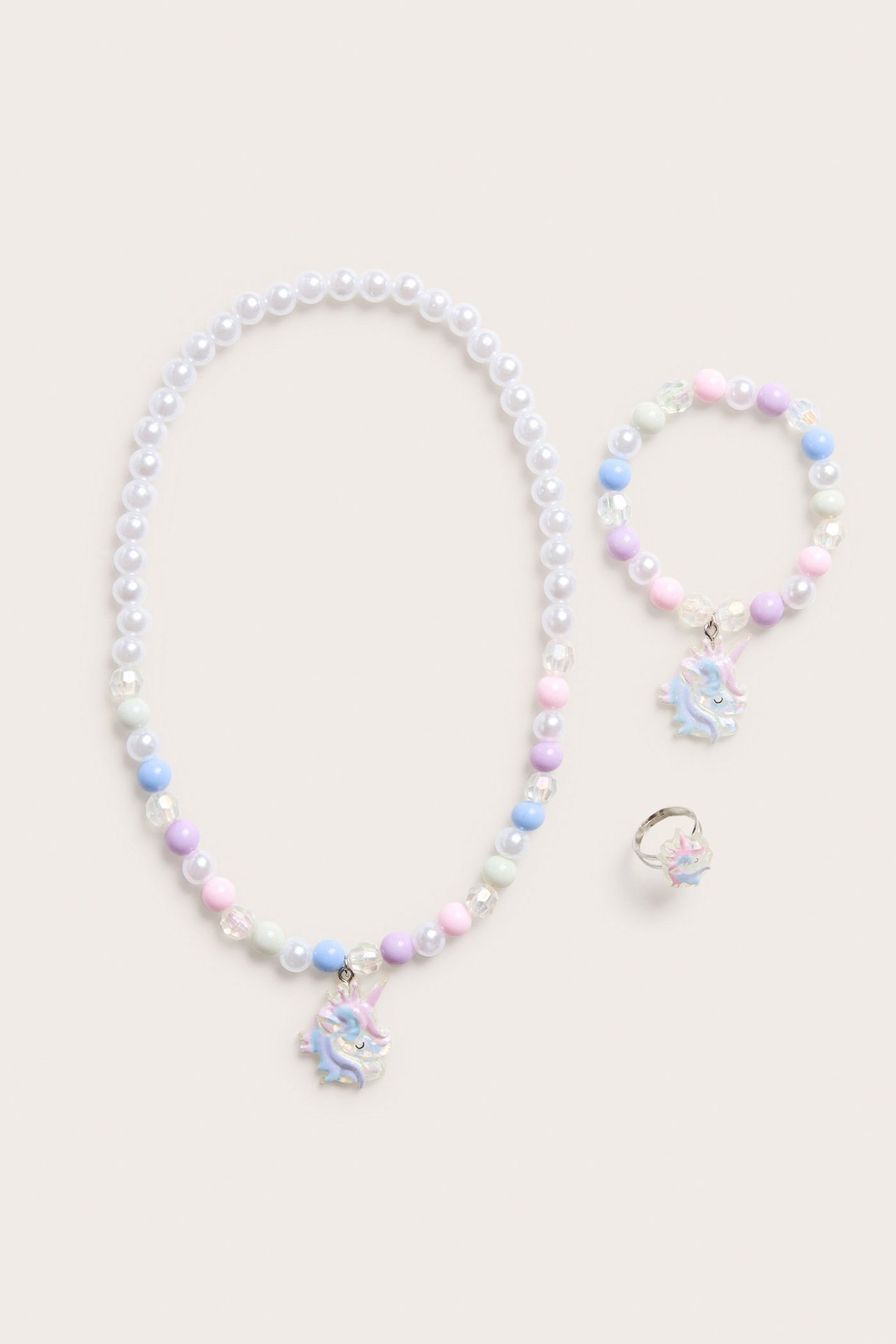 Widok z przodu dziecięcego zestawu: naszyjnik, bransoletka i pierścionek z pastelowych koralików, z jednorożcami.