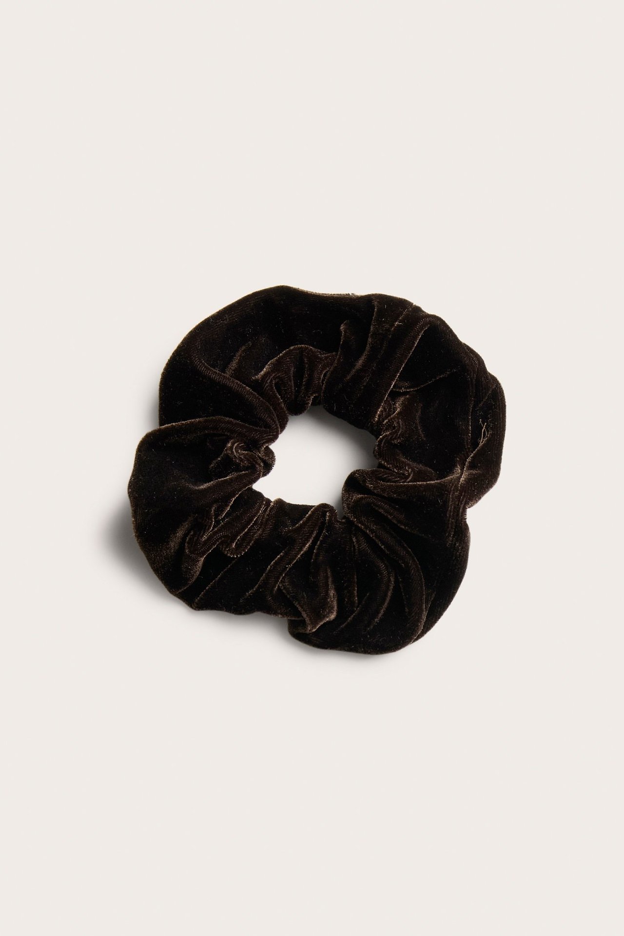 Närbild av en mörkbrun, enfärgad scrunchie i velour.
