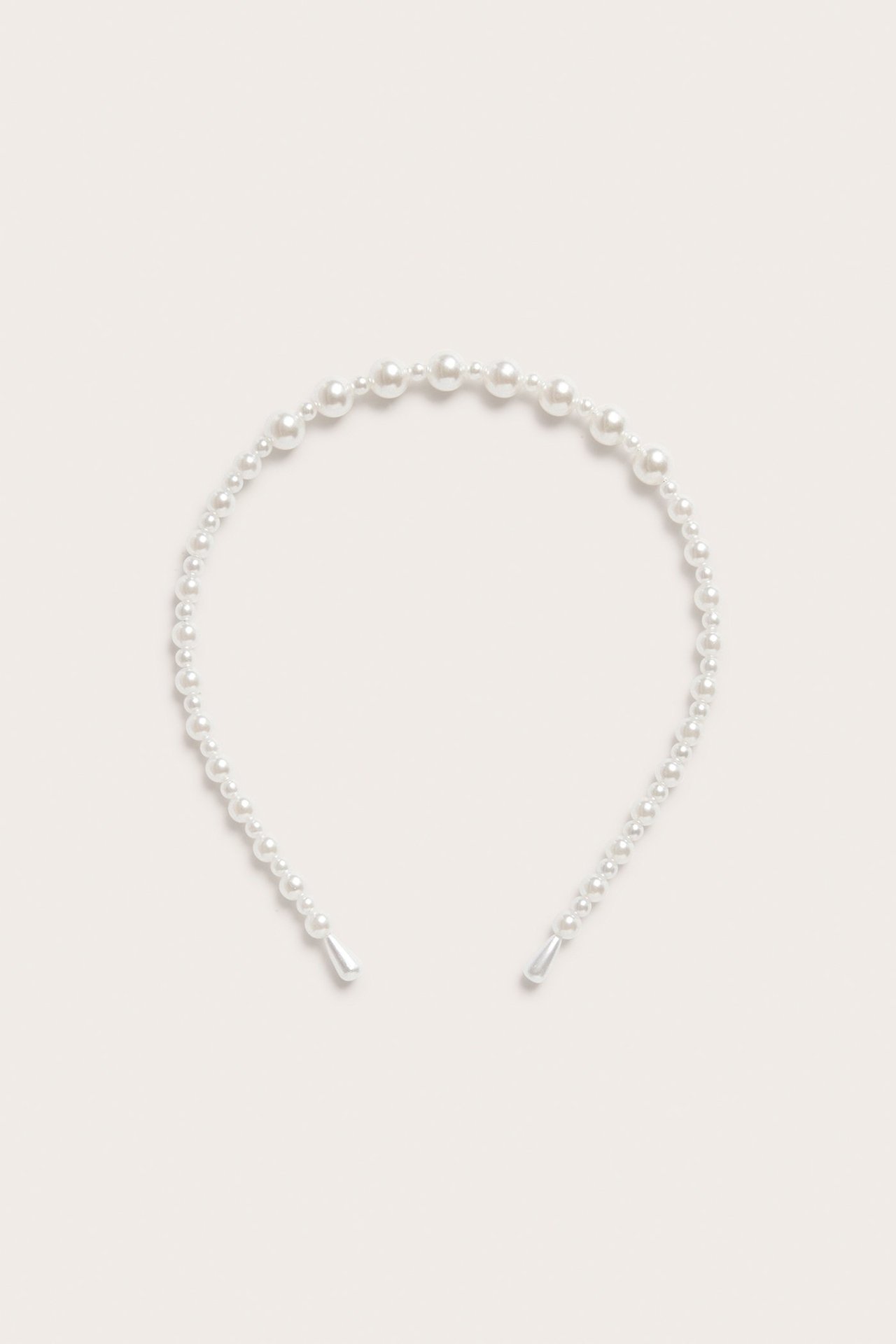 Widok z góry na opaskę w kolorze złamanej bieli, ozdobioną perłami o różnej wielkości.