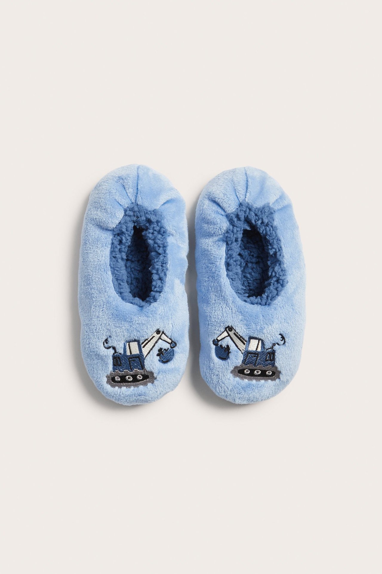Widok z góry na jasnoniebieskie welurowe kapcie dziecięce z granatową podszewką z polaru i haftowaną koparką.