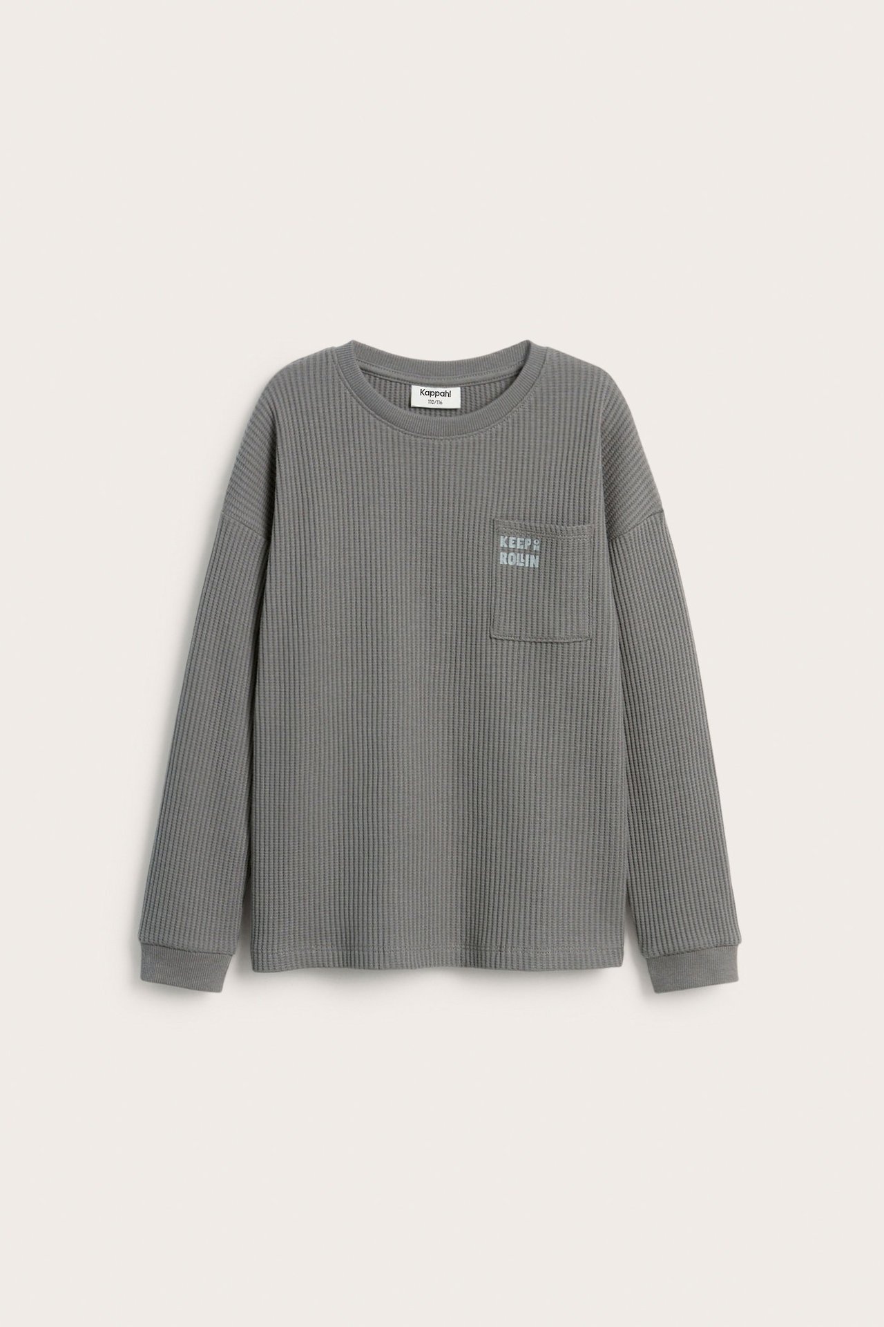 Frontvisning av en grå vaffelstrukturert langermet barneskjorte med senkede skuldre og brystlomme med trykk.