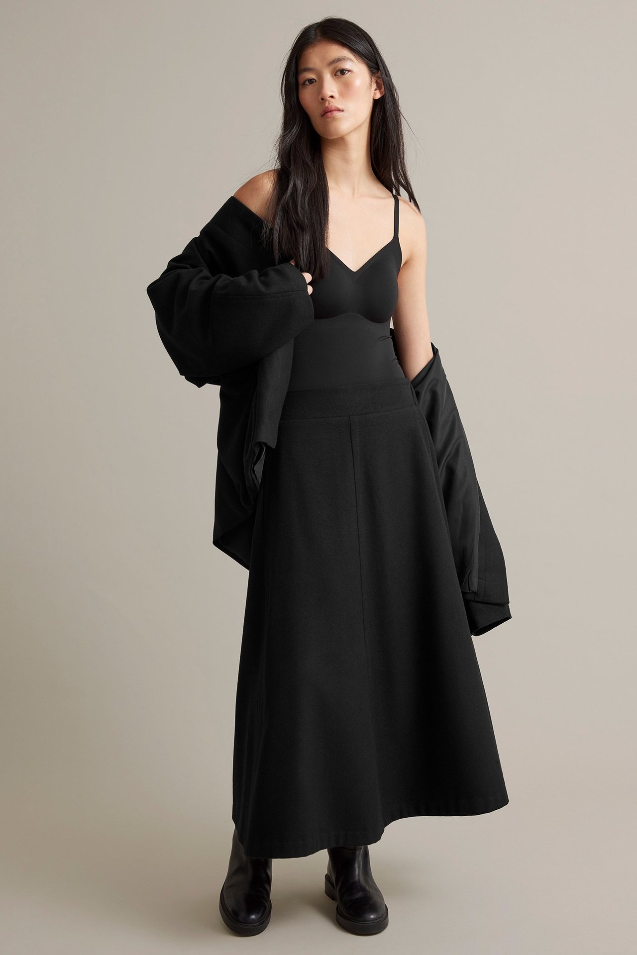 Nainen mustassa villasekoiteklussassa, sivutaskut, joustava vyötärö, ylä ja jakku päälle.