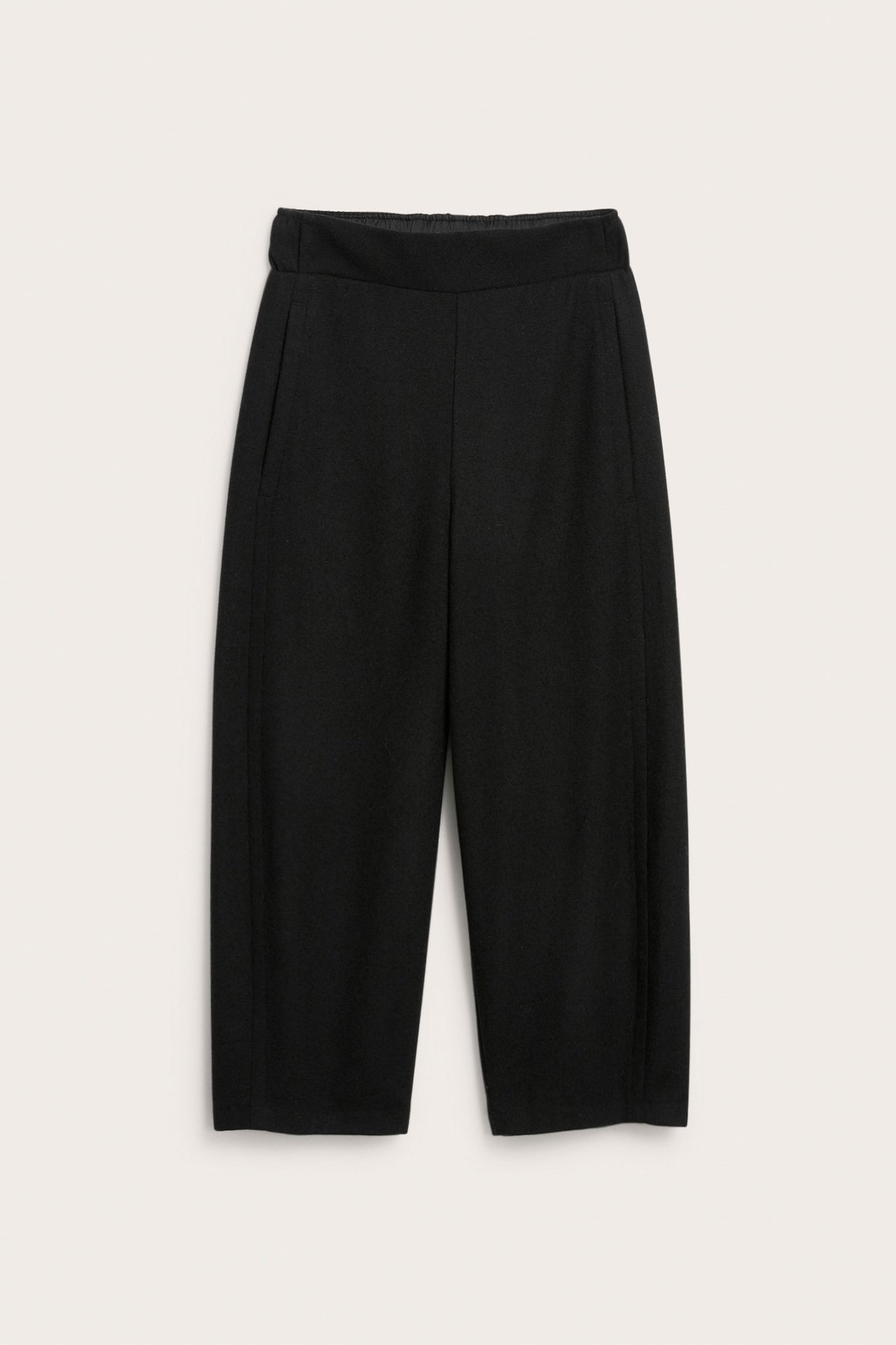 Edestä mustat villasekoitehousut joustovyötäröllä ja leveillä, vajaamittaisilla lahkeilla.