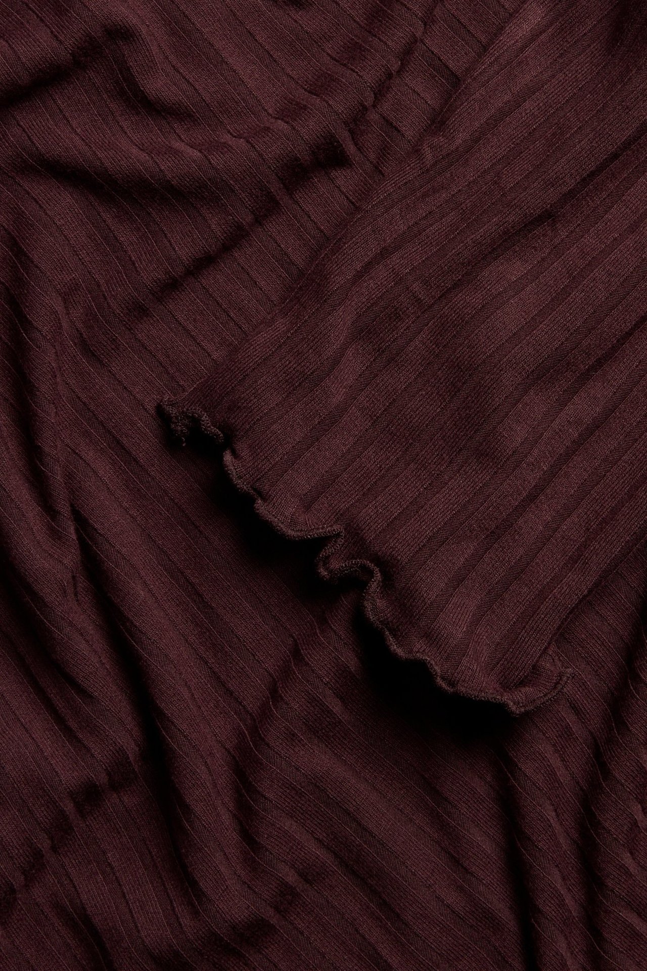 Zbliżenie na bordową prążkowaną tunikę z falbankami, wykonaną z mieszanki wiskozy.