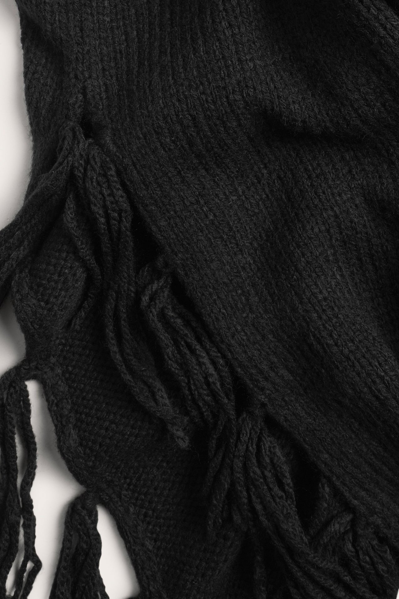 Zbliżenie czarnej dzianinowej kamizelki z frędzlami.