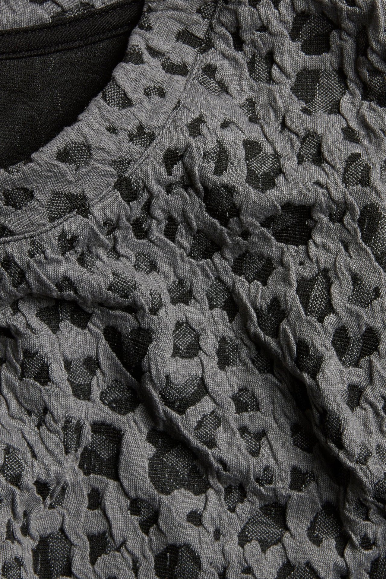 Zbliżenie szarego topu żakardowego z teksturowanym zwierzęcym wzorem.