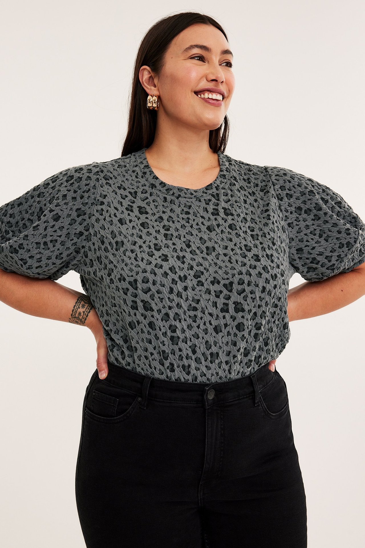 Kobieta w szarym topie jacquard z wzorem zwierzęcym, krótki rękaw, luźny krój.