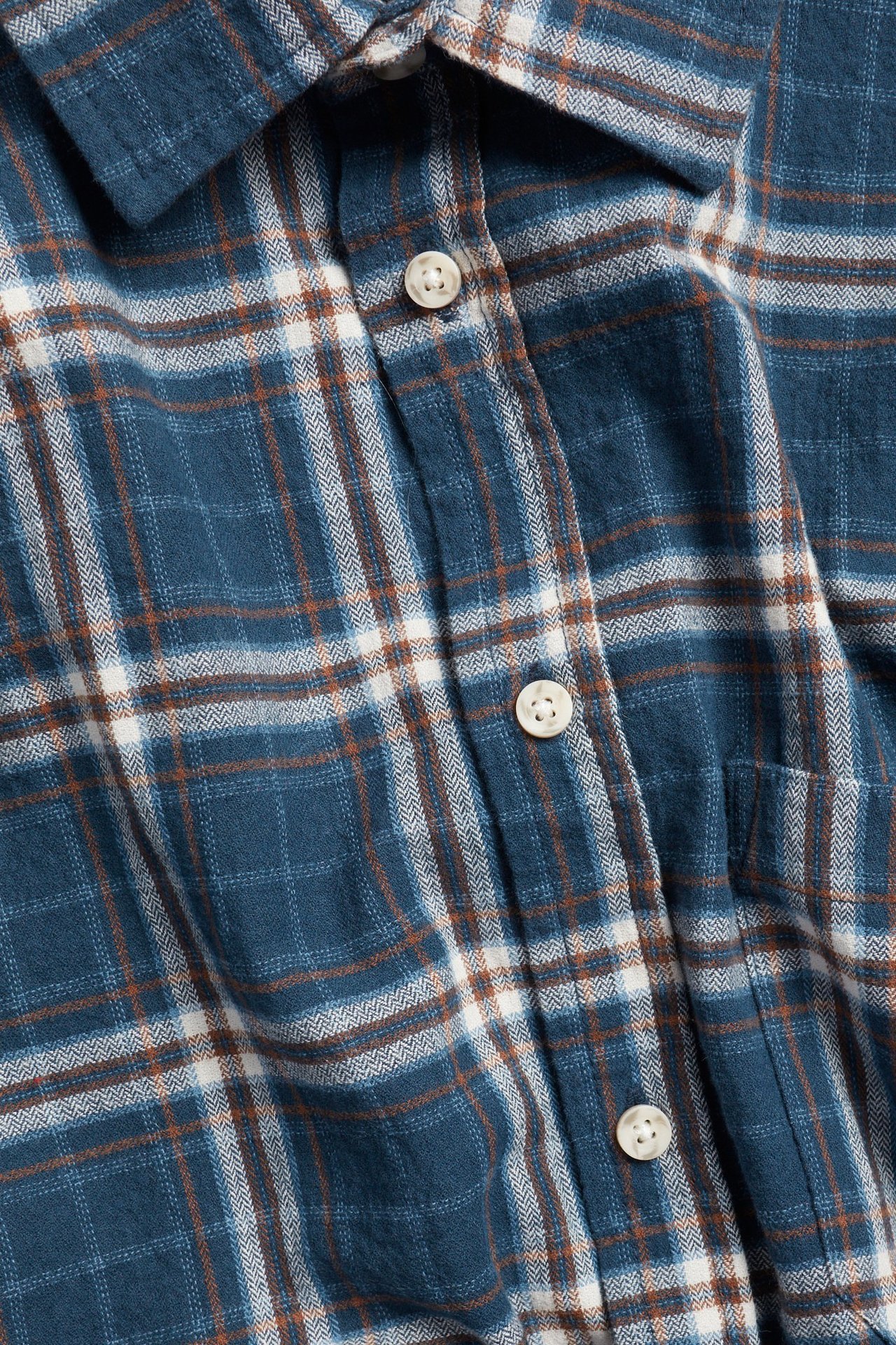 Zbliżenie z przodu na granatową, biało-brązową koszulę w kratę z mieszanki bawełny z białymi guzikami.