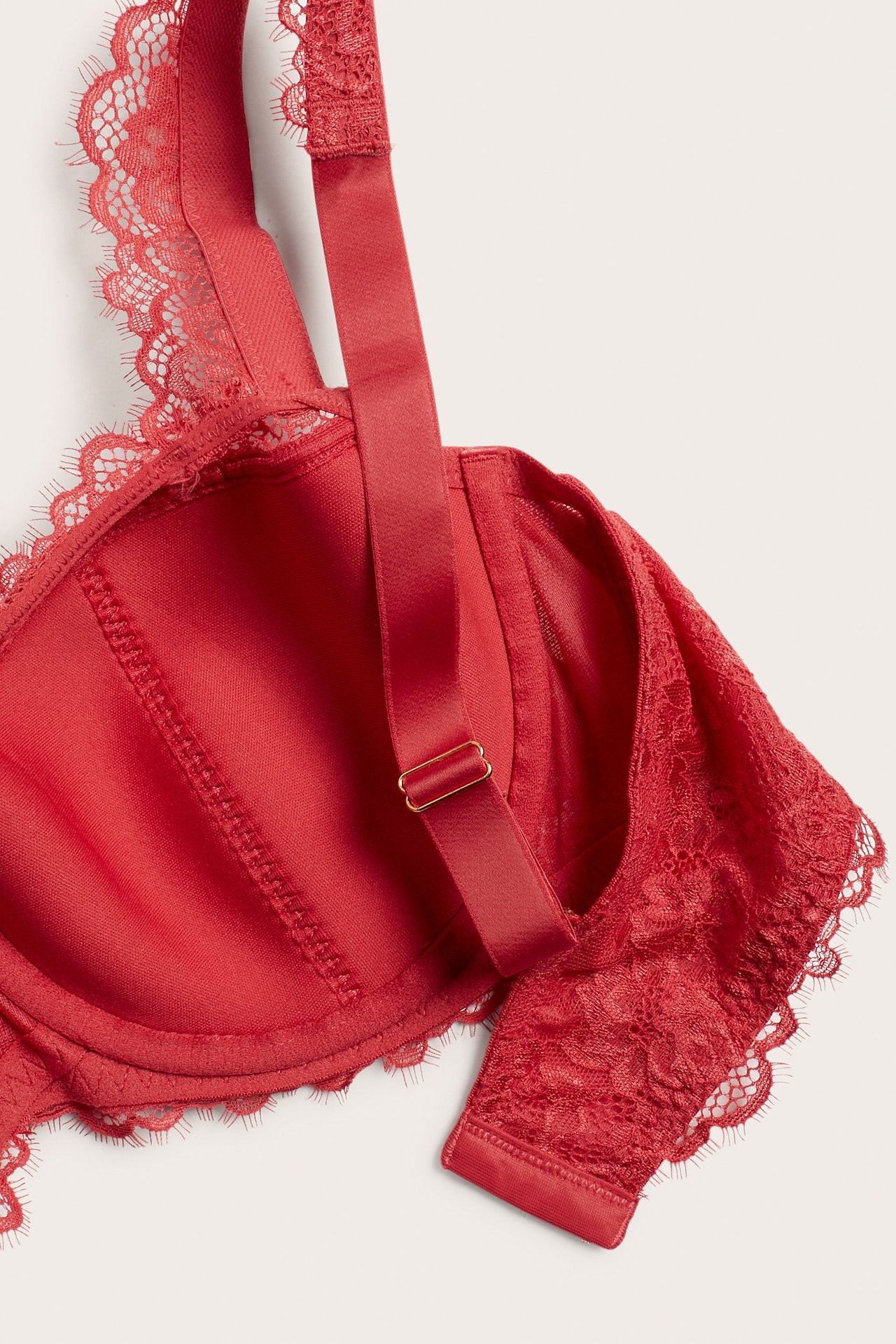 Zbliżenie czerwonego koronkowego biustonosza typu balconette z regulowanymi ramiączkami i kwiatowym wzorem.