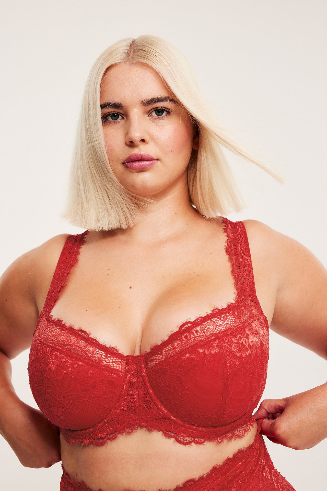 Nainen punaisessa pitsiliivissä, haaravi Här balconette-bh ja säädettävät nauhat.