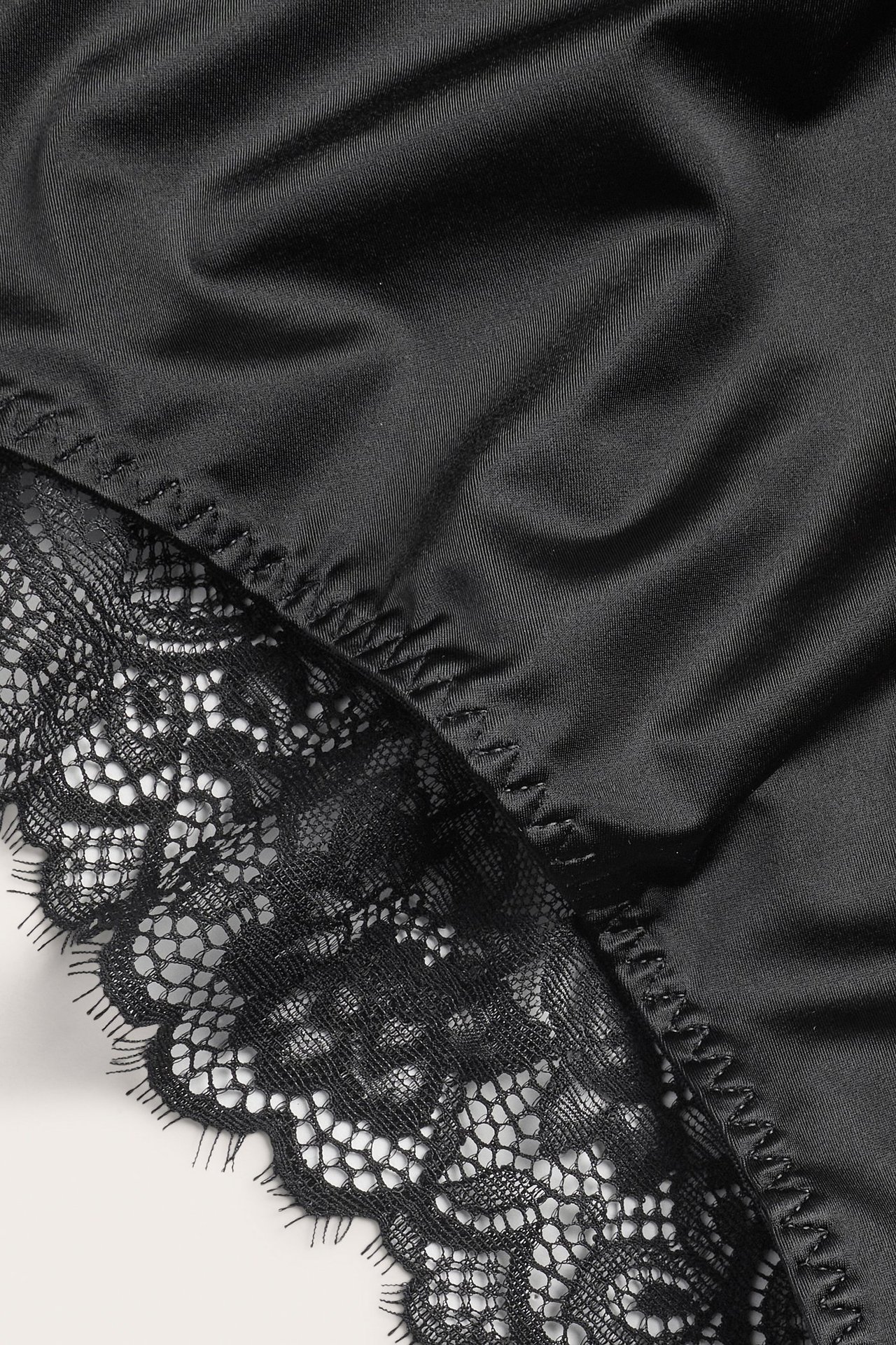 Zbliżenie czarnych, elastycznych majtek z mikrosatyny z delikatnym czarnym koronkowym brzegiem.