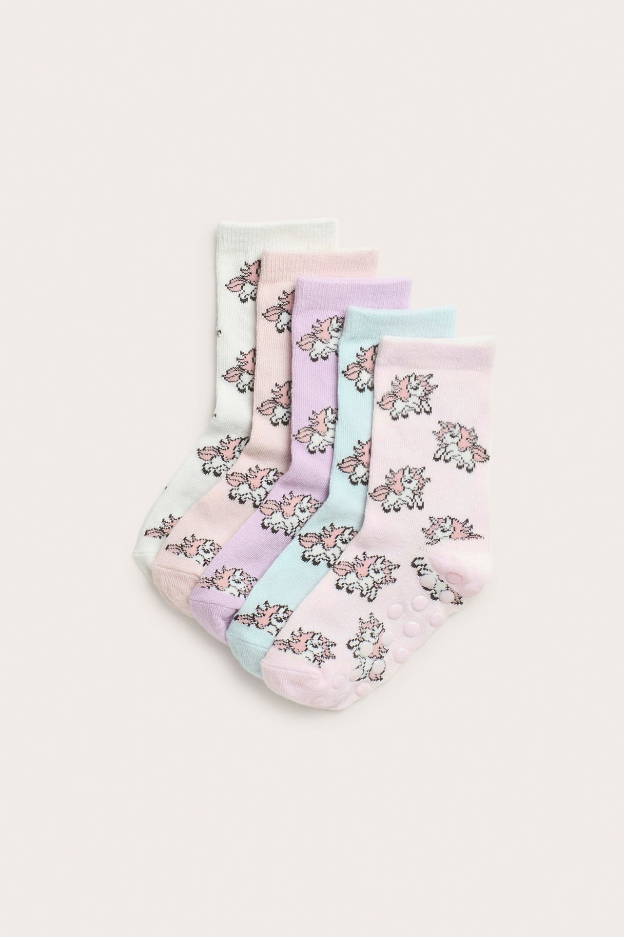 Widok z góry na pięć dziecięcych skarpetek w pastelowych kolorach z wzorem jednorożców i antypoślizgowymi podeszwami.