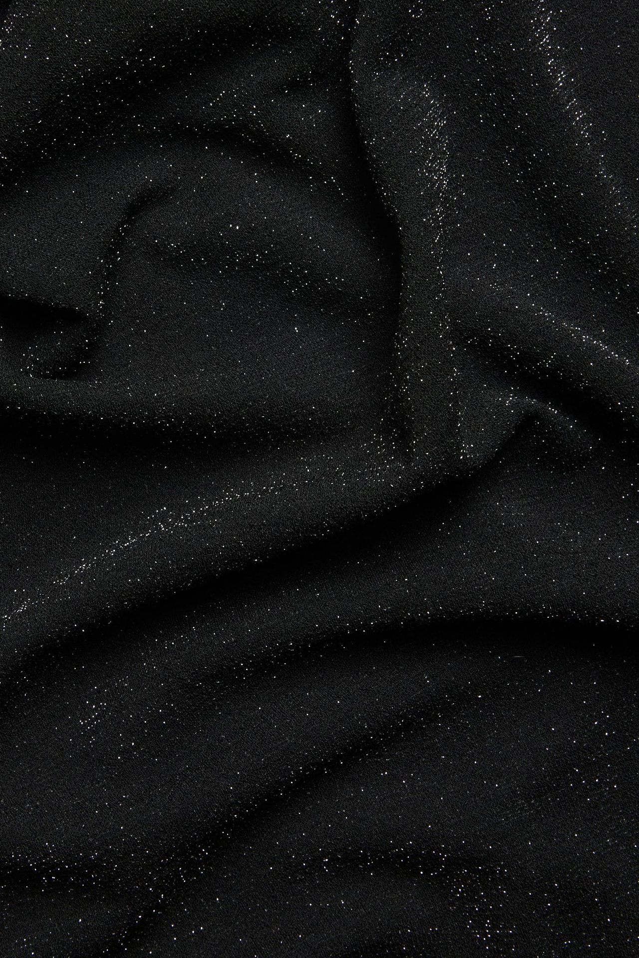 Zbliżenie na udrapowany czarny, brokatowy materiał na top z lurexu.