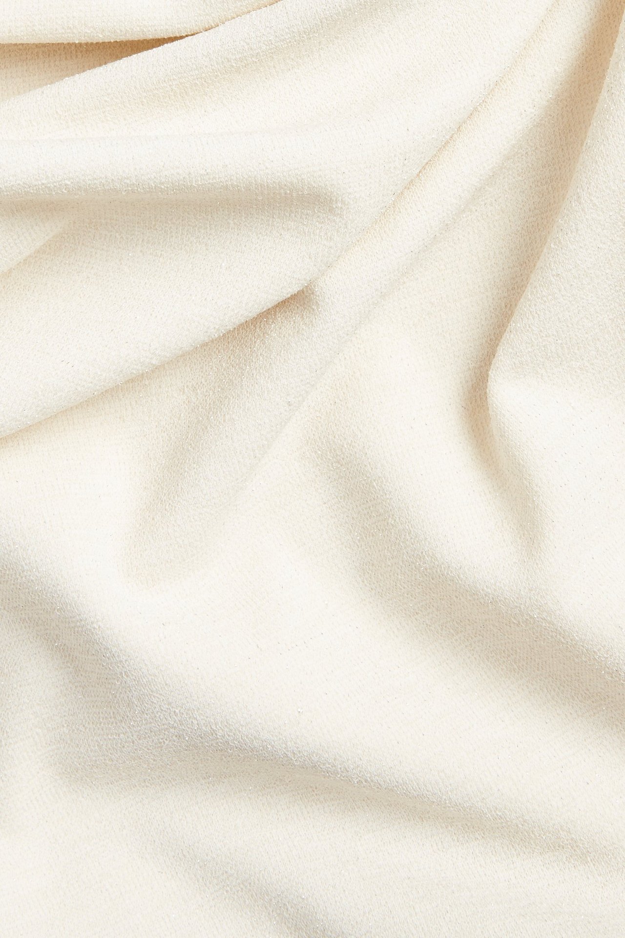 Zbliżenie na kremowy, brokatowy, drapowany materiał na bluzkę z efektem wodospadu.