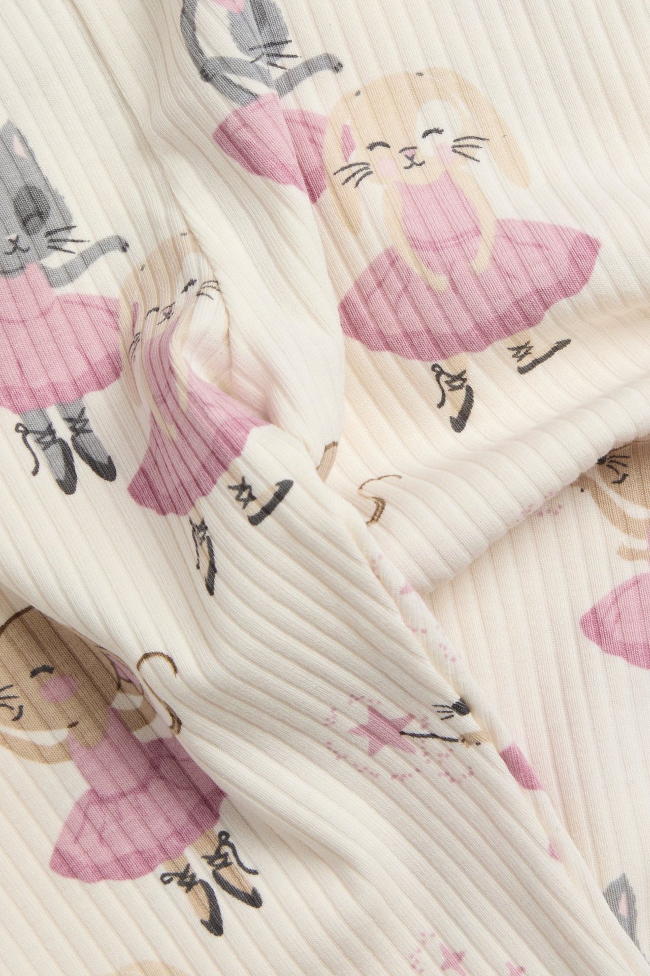 Zbliżenie prążkowanych legginsów w kolorze ecru ze wzorem baletnic: królików, kotów i myszy.