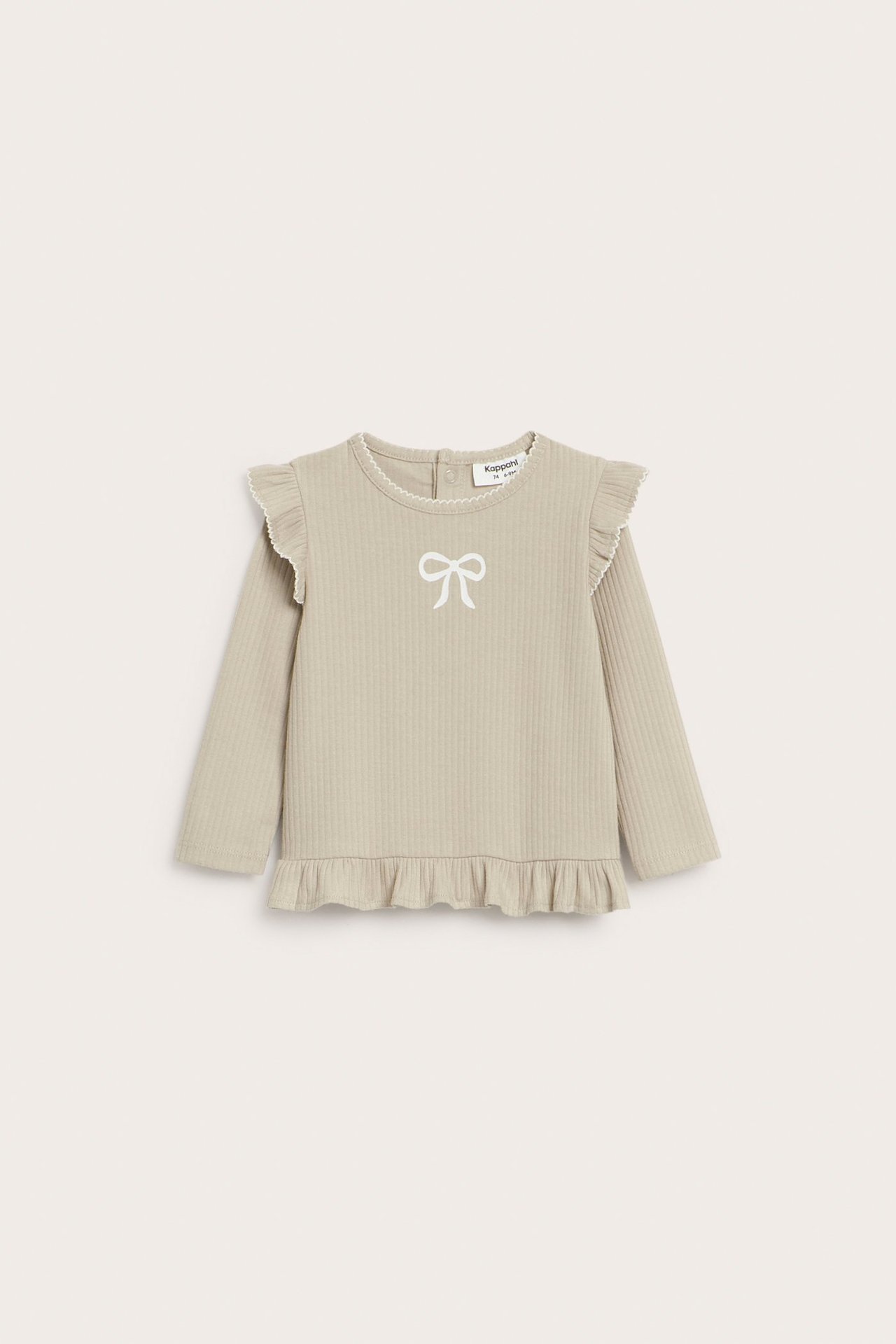 Forfra: Babys beige ribbestrikkede langermede topp med hvitt sløyfemønster, volanger og picotkanter.