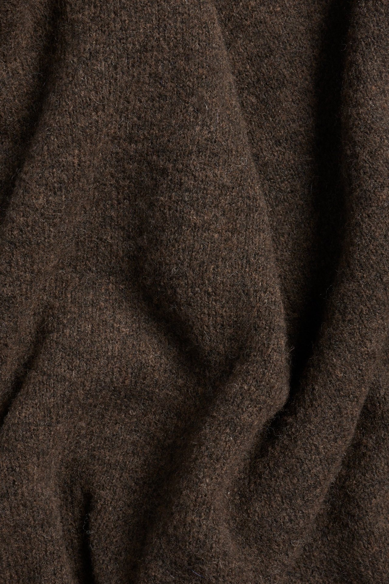 Zbliżenie na ciemnobrązowy dzianinowy materiał długiej sukienki z golfem.