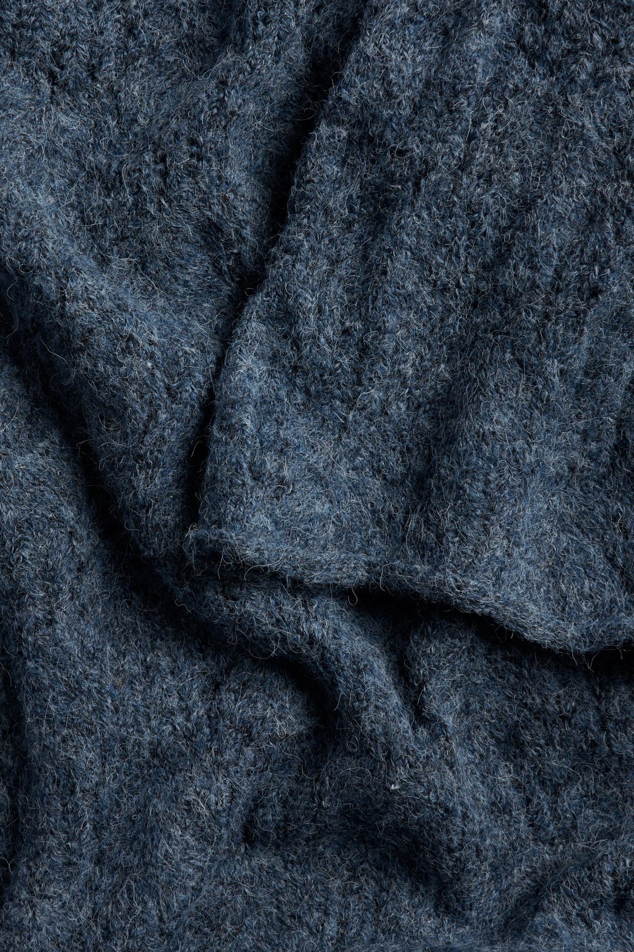Zbliżenie na ciemnoniebieski dzianinowy materiał sukienki o puszystej fakturze.