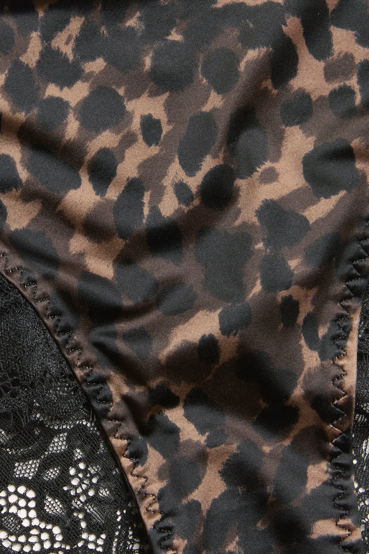 Zbliżenie na damskie figi z czarno-brązowym wzorem w cętki i czarnymi koronkowymi detalami.