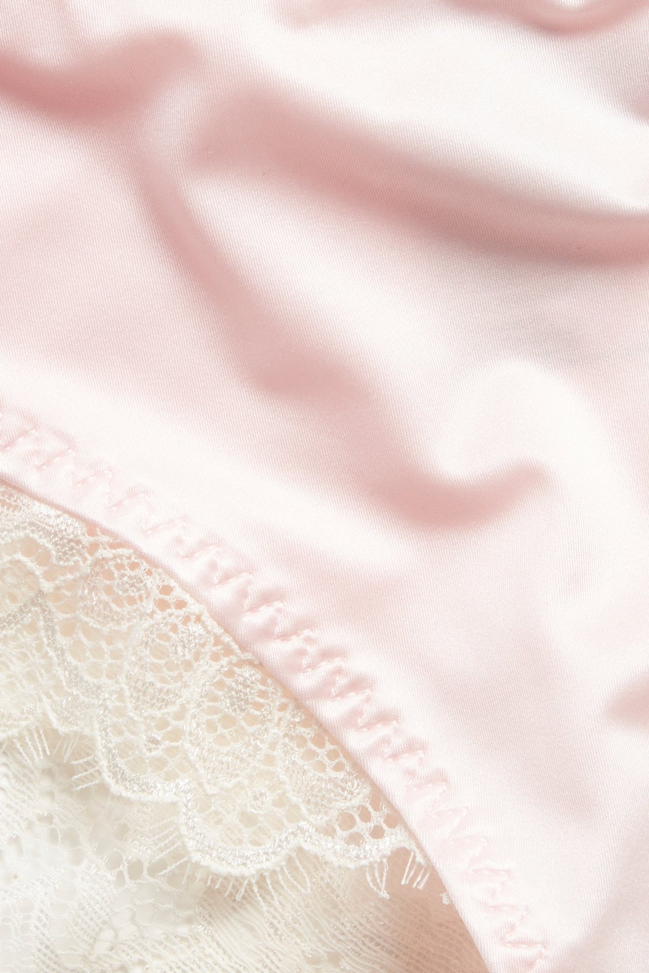 Lähikuva vaaleanpunaisista mikrokuitupikkuhousuista valkoisilla pitsiyksityiskohdilla.