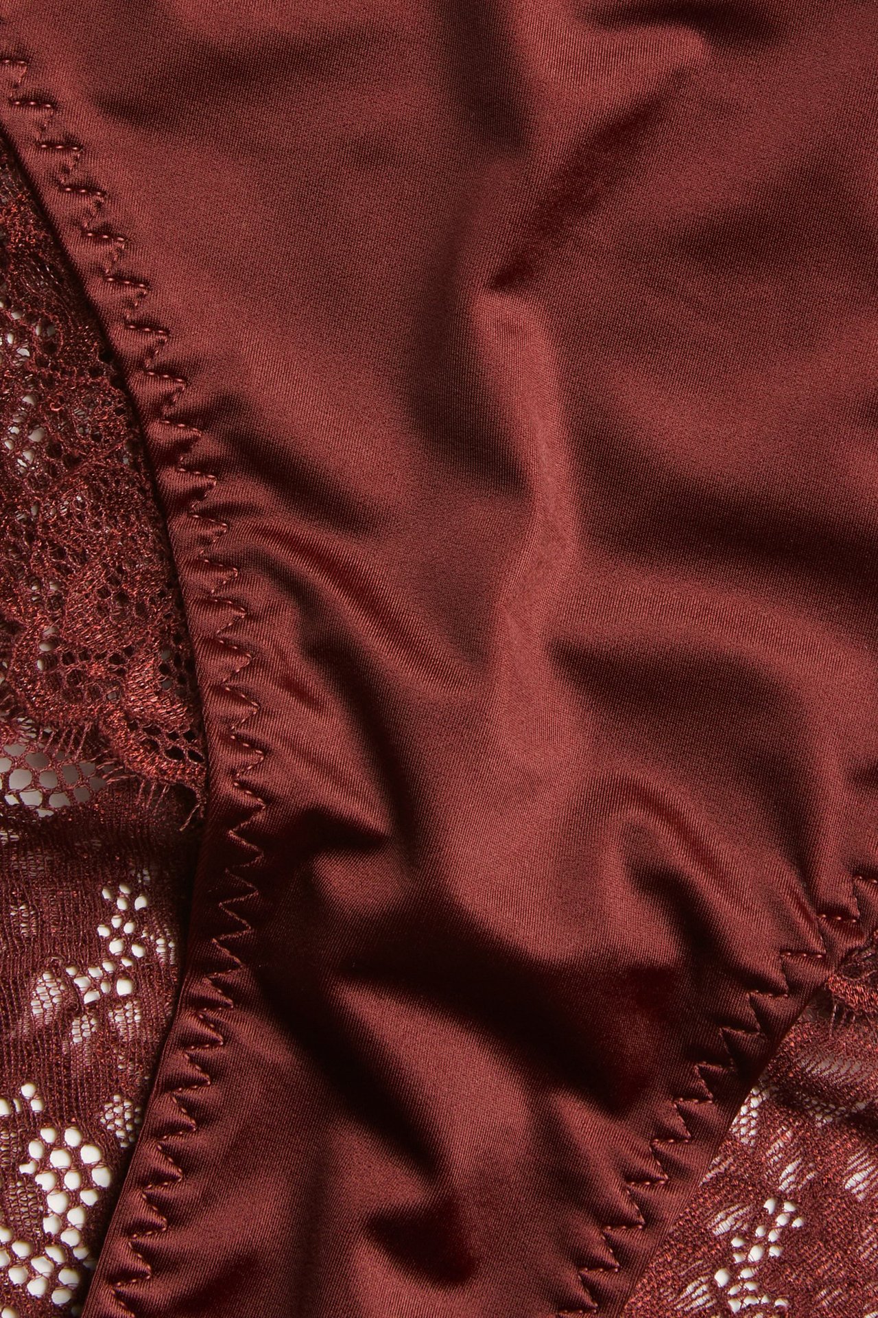 Zbliżenie na czerwone figi midi z delikatnymi koronkowymi detalami, wykonane z mikrofibry.