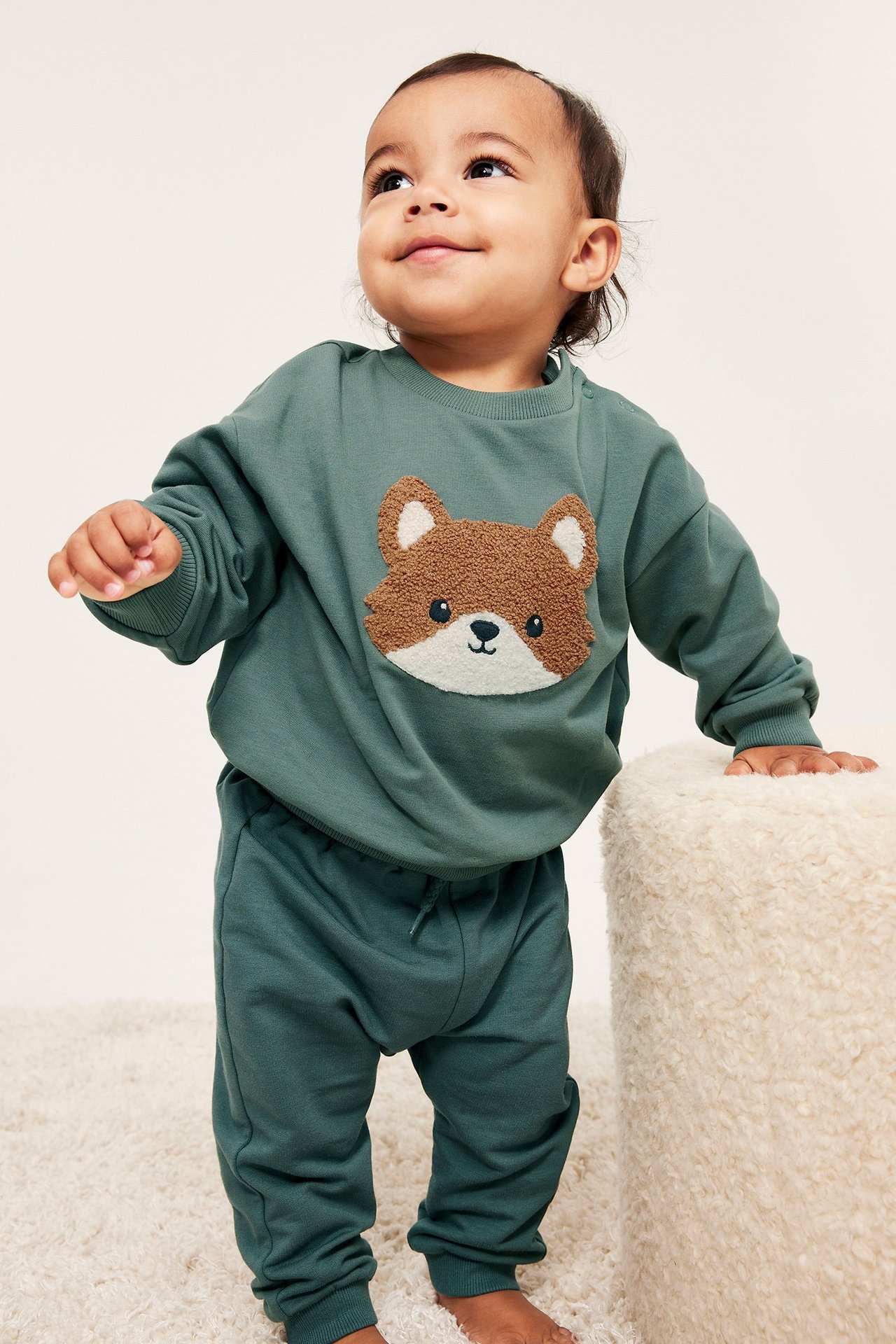 Edestä näkymä vauvasta yllään khakinvihreä collegepaita froteekettusovelluksella ja yhteensopivat collegehousut.