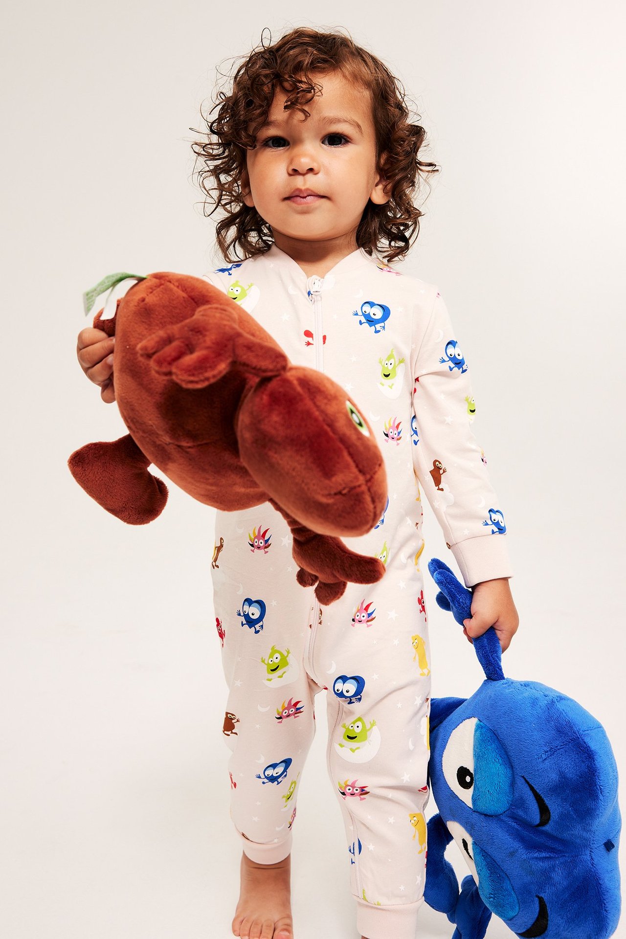 Barn i pyjamas med Babblarna-motiv, hållandes stora mjukisdjur, frontvy.