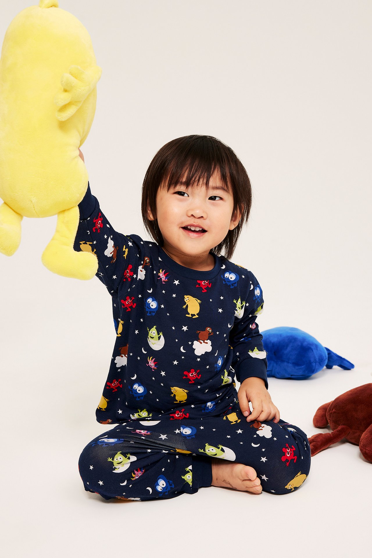 Liten pojke i mörkblå pyjamas med Babblarna-motiv, sittande med leksaker.