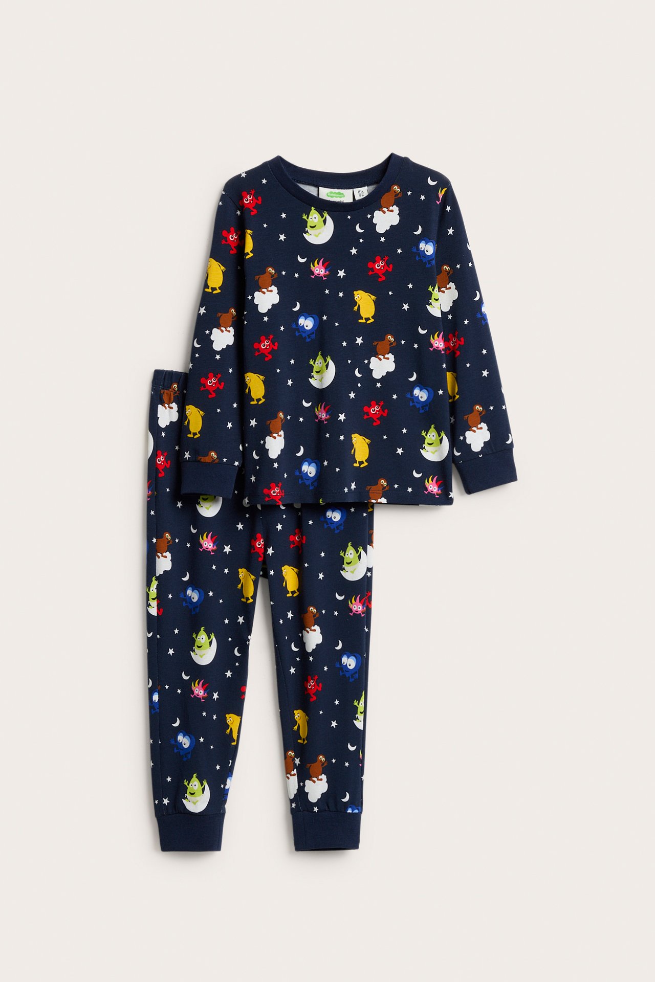 Framifrån, mörkblå barnpyjamas med långa ärmar och byxor, med färgglada Babblarna-karaktärer, månar och stjärnor.