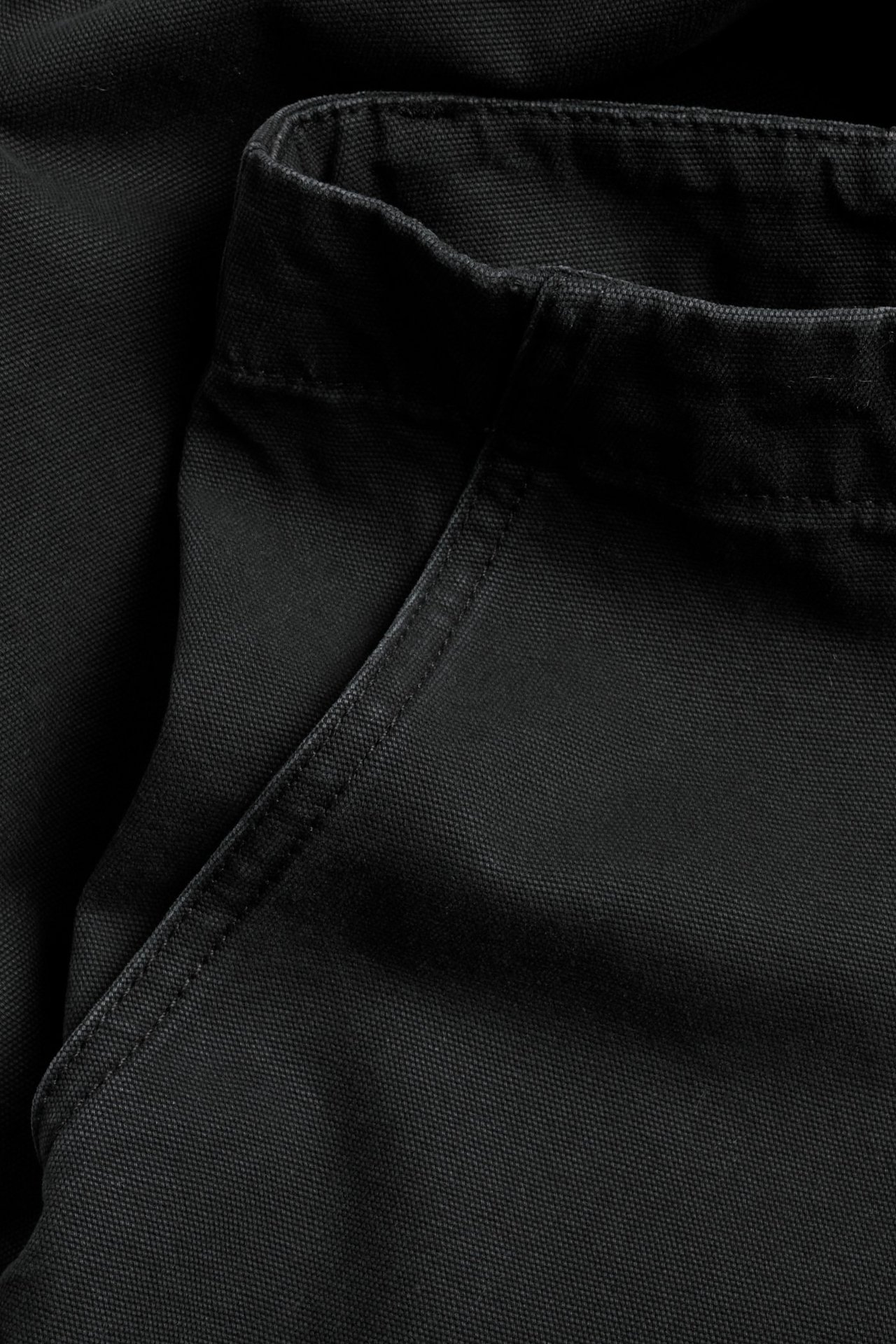 Zbliżenie czarnych, ciężkich bawełnianych spodni roboczych z widoczną kieszenią i paskiem.