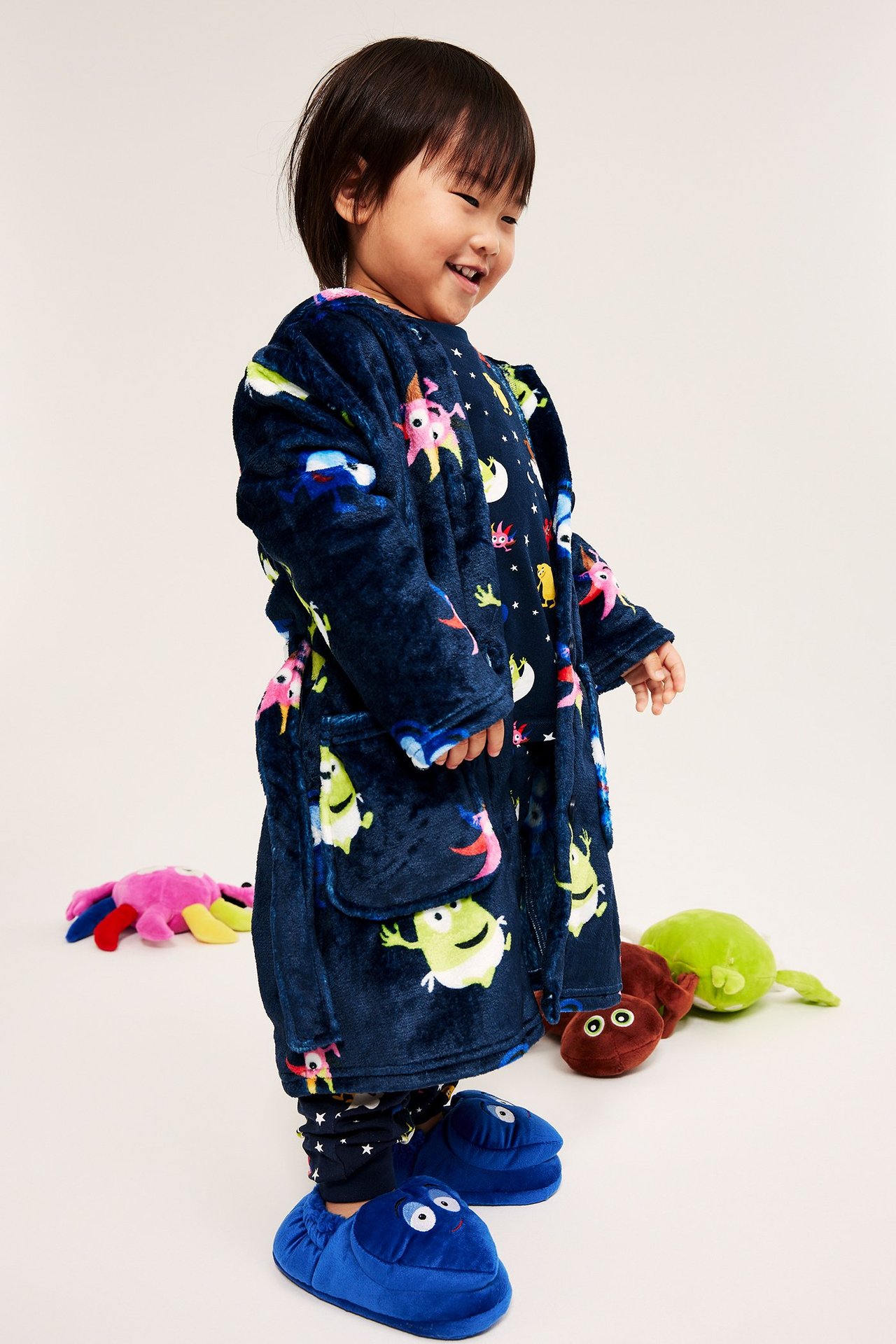 Dziecko w ciemnoniebieskim kocie Babblarna, z fleece, z przodu, w niebieskich kapciach.