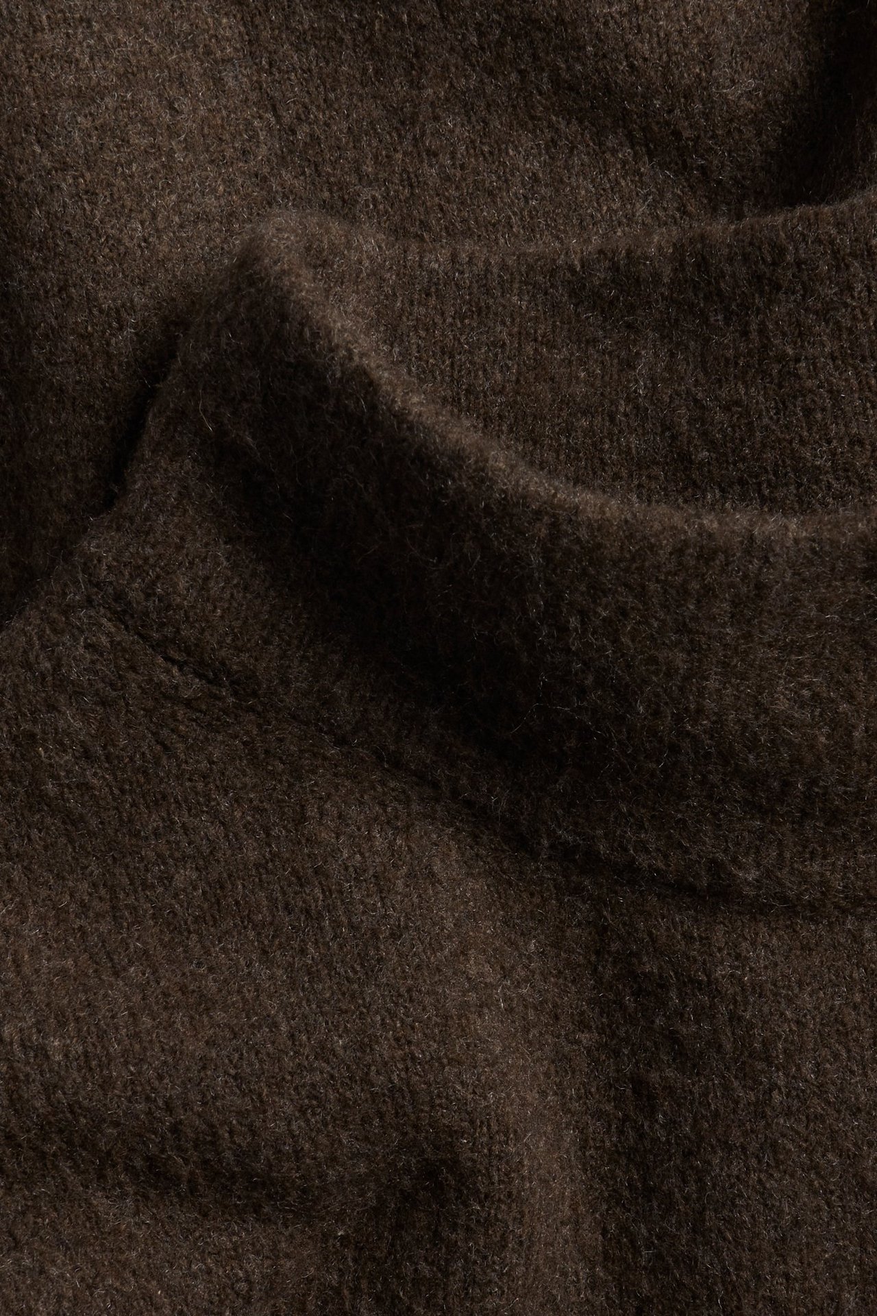 Zbliżenie na ciemnobrązowy, strukturalny sweter z golfem.