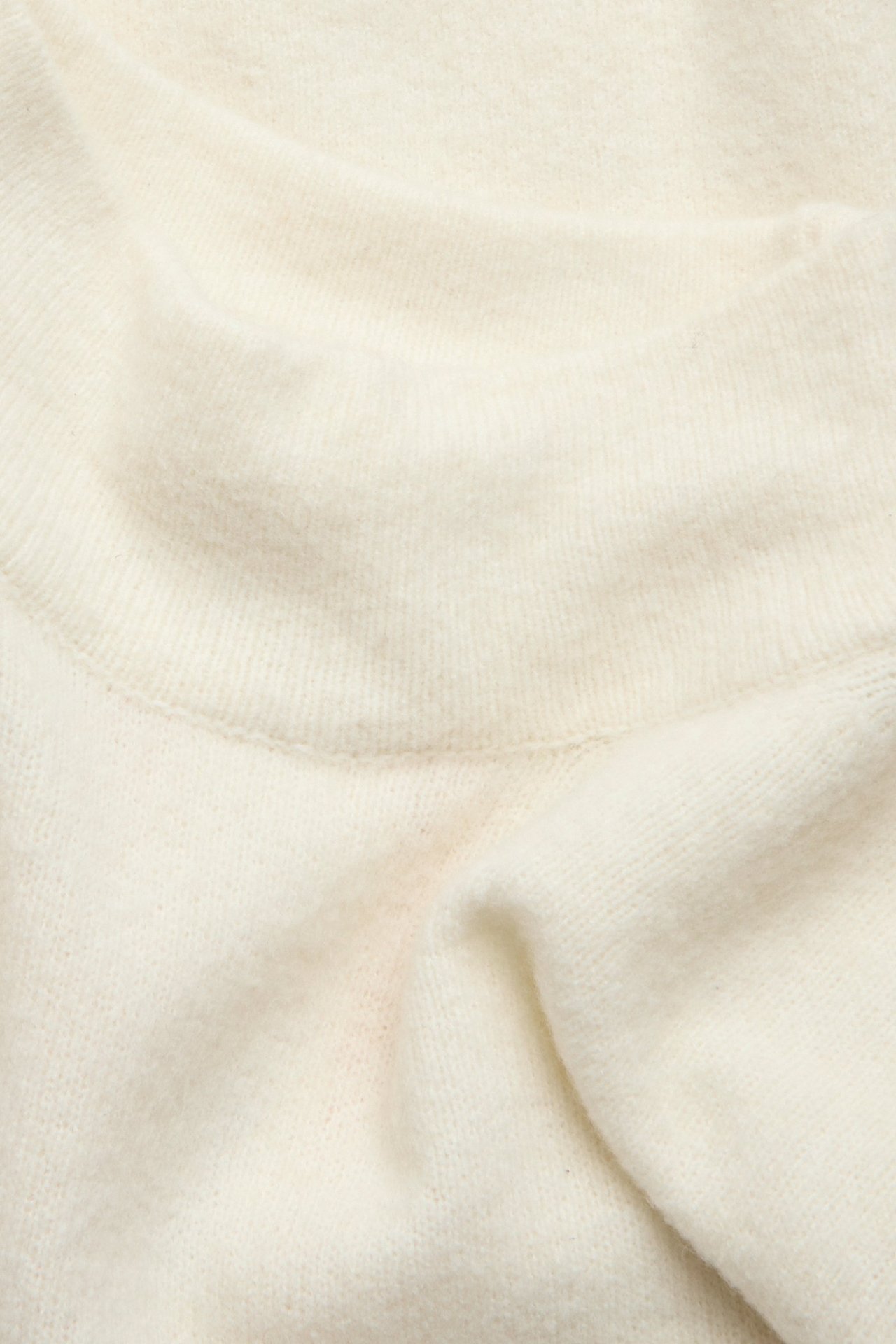 Zbliżenie na jasnobeżowy, strukturalny golf z dzianiny.