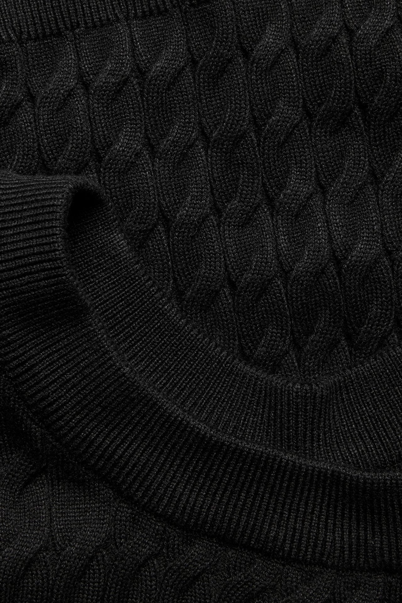 Zbliżenie czarnego swetra z warkoczowym splotem i ściągaczami.