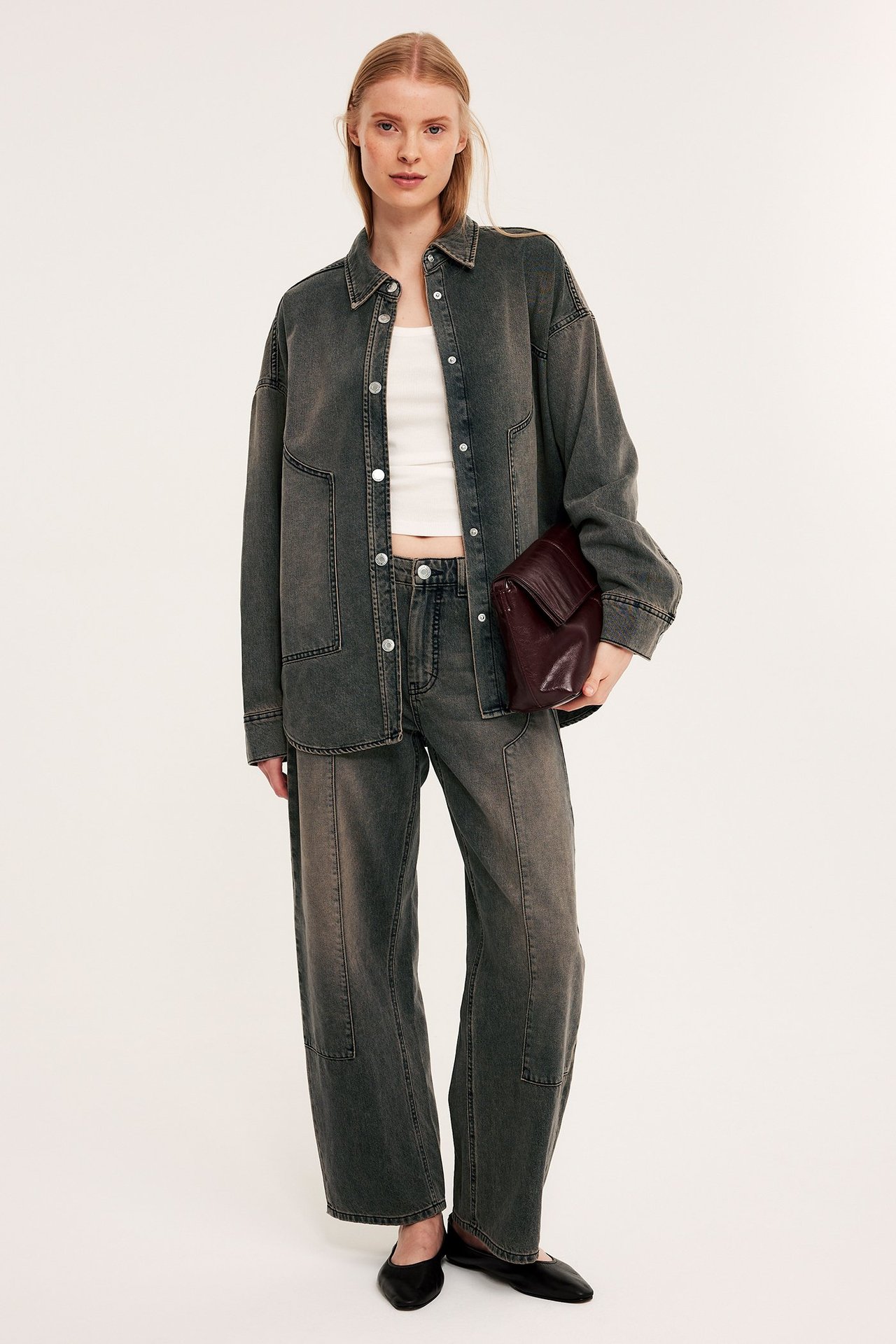 Framifrån: Urtvättad svart oversized jeansskjorta, matchande jeans, vit topp, svarta ballerinaskor, vinröd clutch.