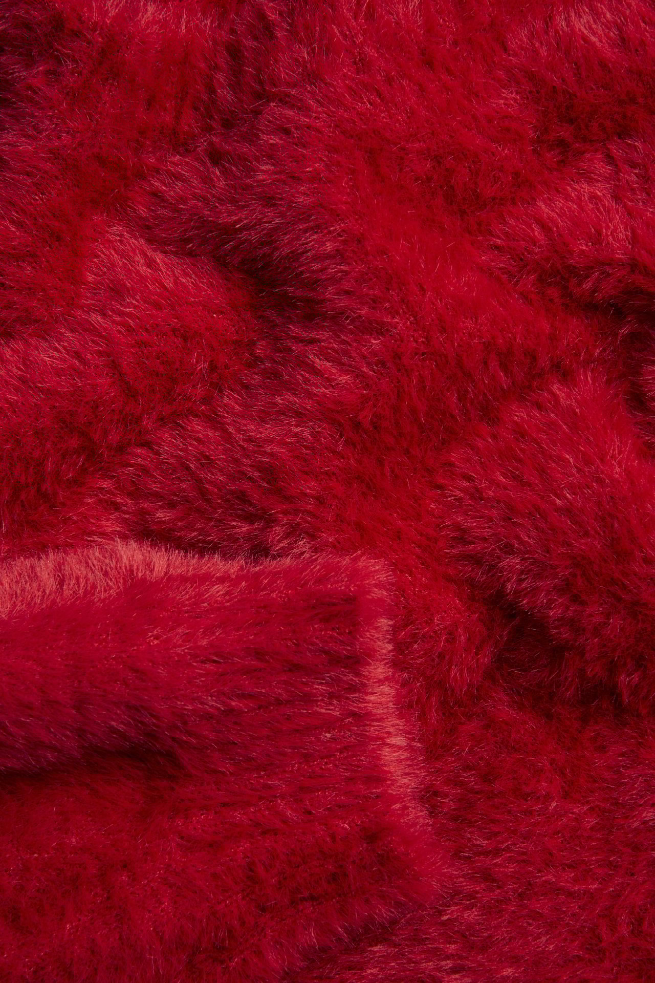 Zbliżenie na czerwony sweter dzianinowy z miękkiej przędzy piórkowej.