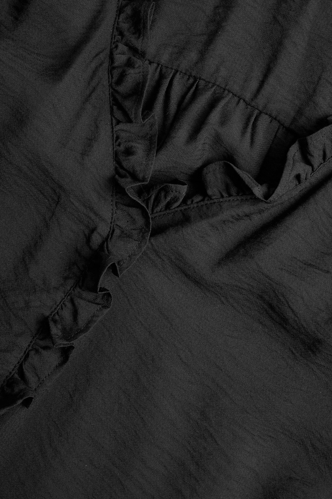 Zbliżenie czarnej bluzki z mieszanki wiskozy z falbankami.