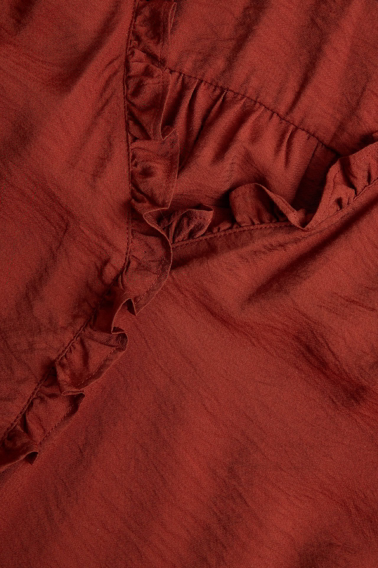 Zbliżenie czerwonej bluzki z mieszanki wiskozy z falbankami.