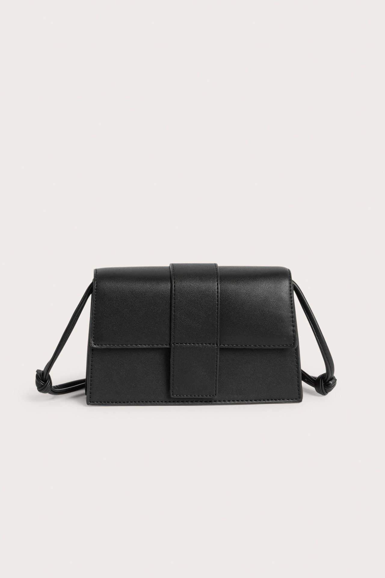 Widok z przodu czarnej torebki na ramię ze sztucznej skóry z klapą i regulowanym paskiem.