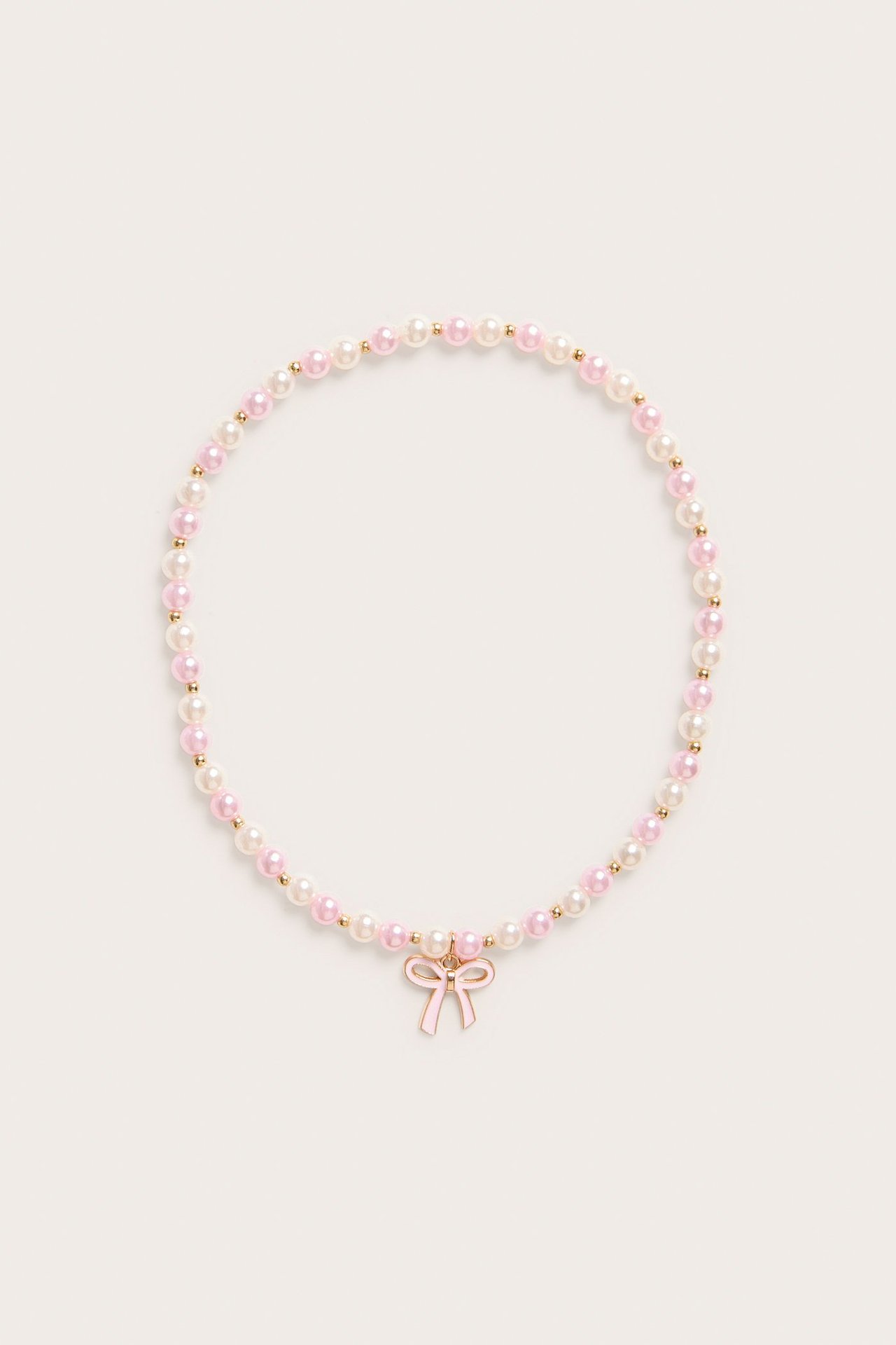 Widok z góry: Naszyjnik z jasnoróżowych i białych pereł z jasnoróżową zawieszką w kształcie kokardki.