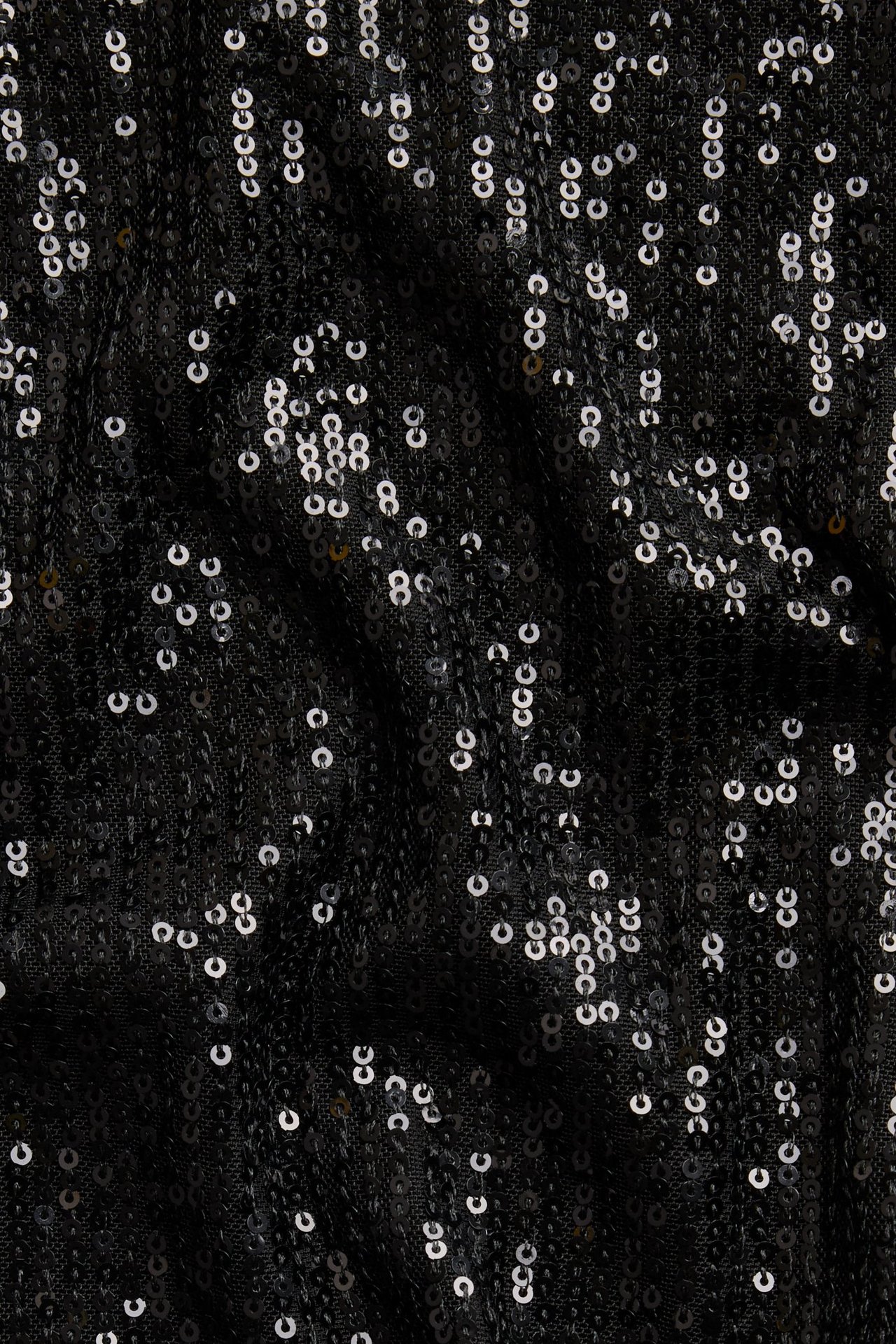 Närbild av en svart kortärmad paljettopp med silverfärgad glitterdetalj.