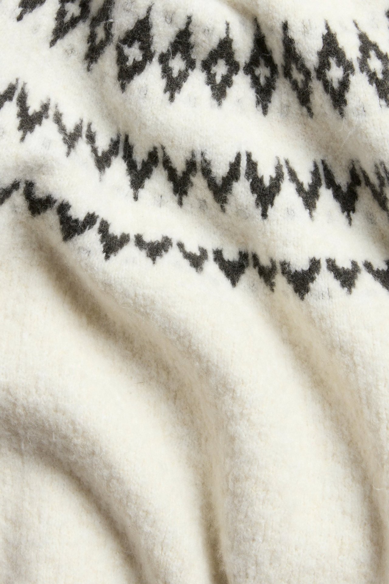 Valkoinen lyhythihainen neulottu paita, fairisle-kuvio, läheltä.