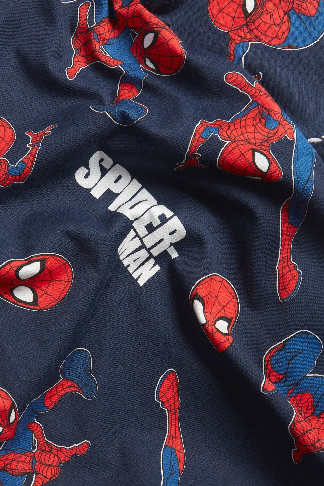 Närbild på en mörkblå bomulls t-shirt för barn med Spiderman-mönster och texten 'SPIDER-MAN'.